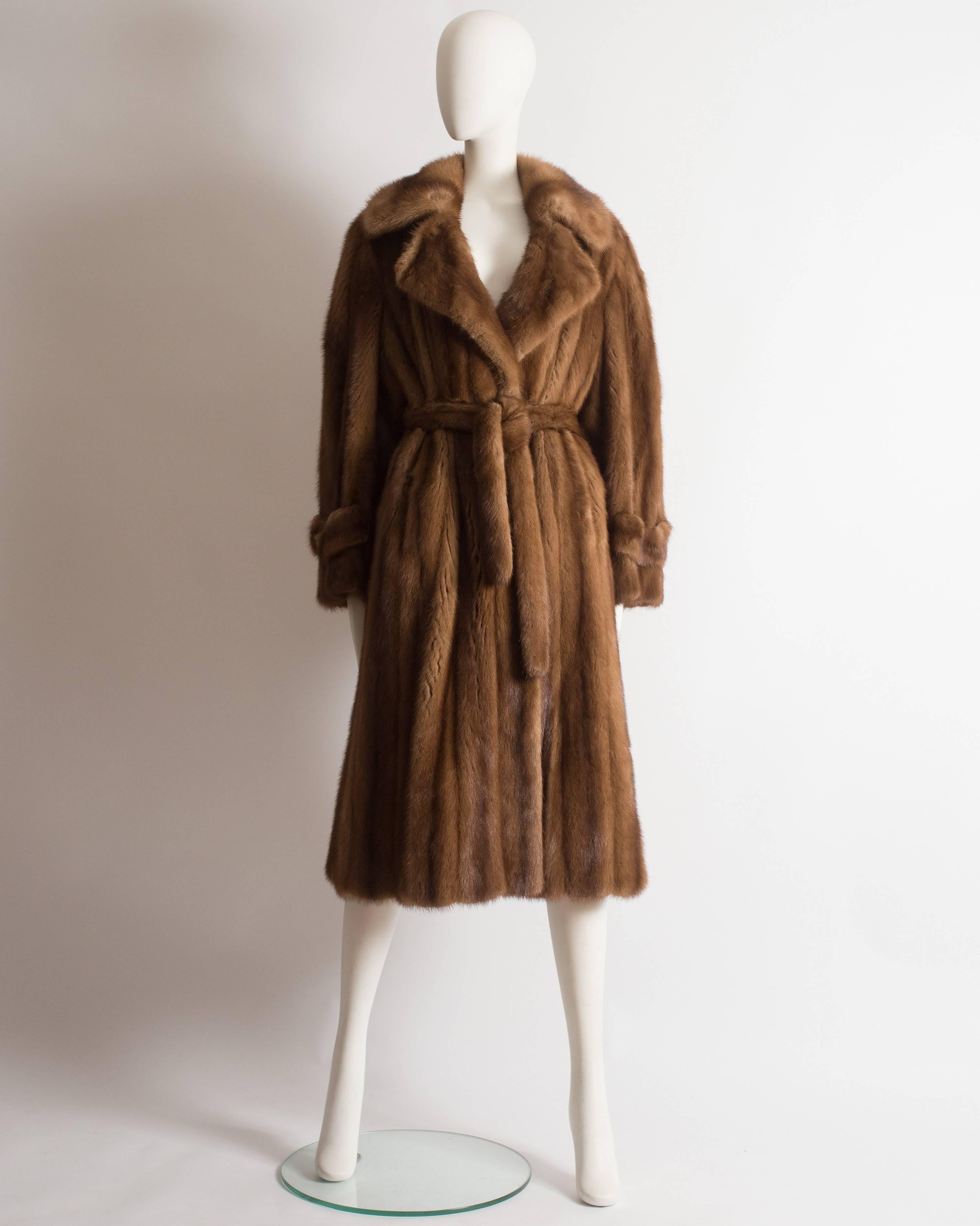Luxurious Christian Dior Haute Couture wild mink coat, circa 1960s. The coat features wooden button closures on the cuffs and collar, matching mink waist belt, two hidden front pockets and large lapels and collar. 

