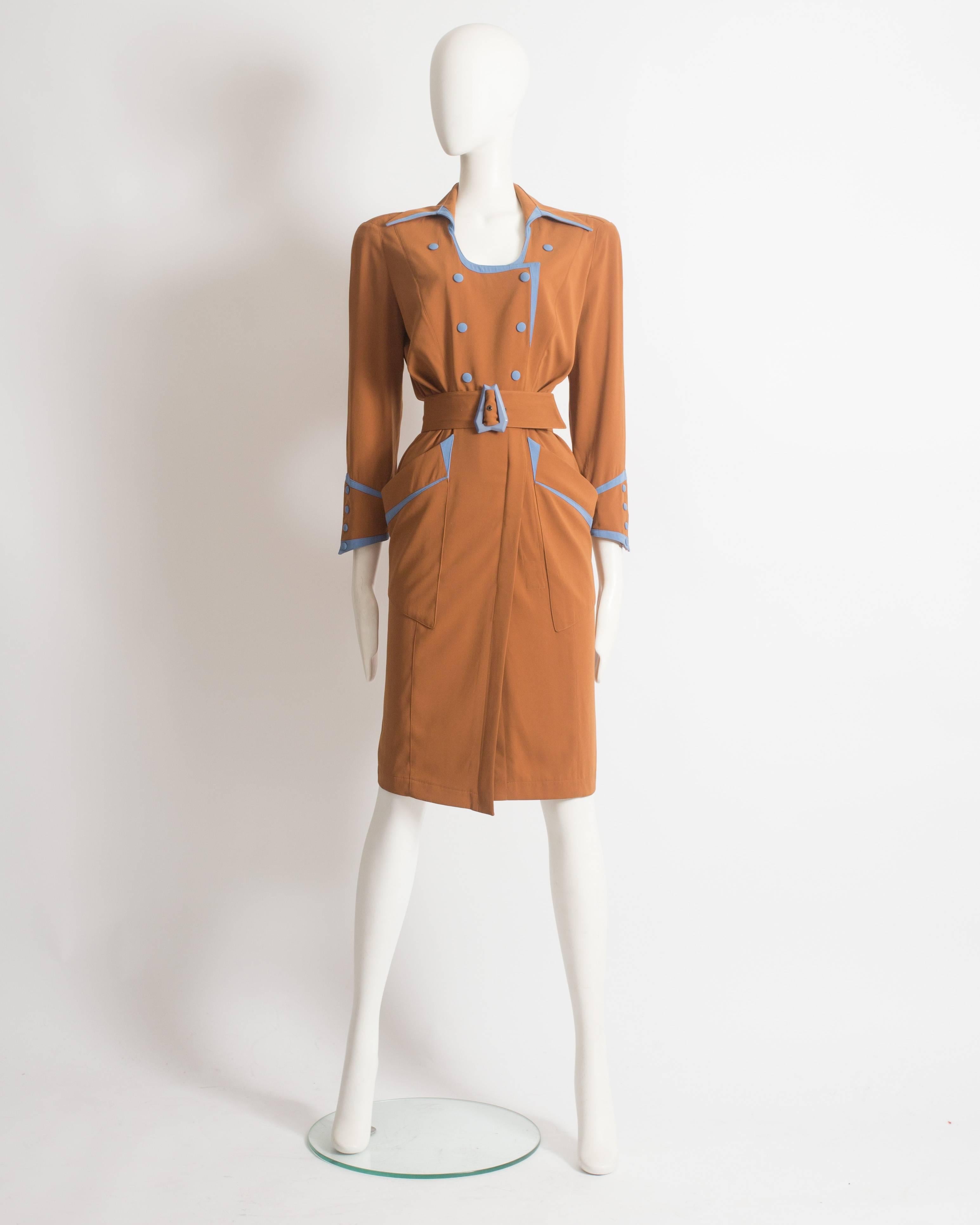 Thierry Mugler shirt dress constructed in mustard gabardine with sky blue trim. Snap button closures throughout, silk satin lining, long point collar with scoop neck, internal shoulder pads, two large front pockets and matching belt with blue