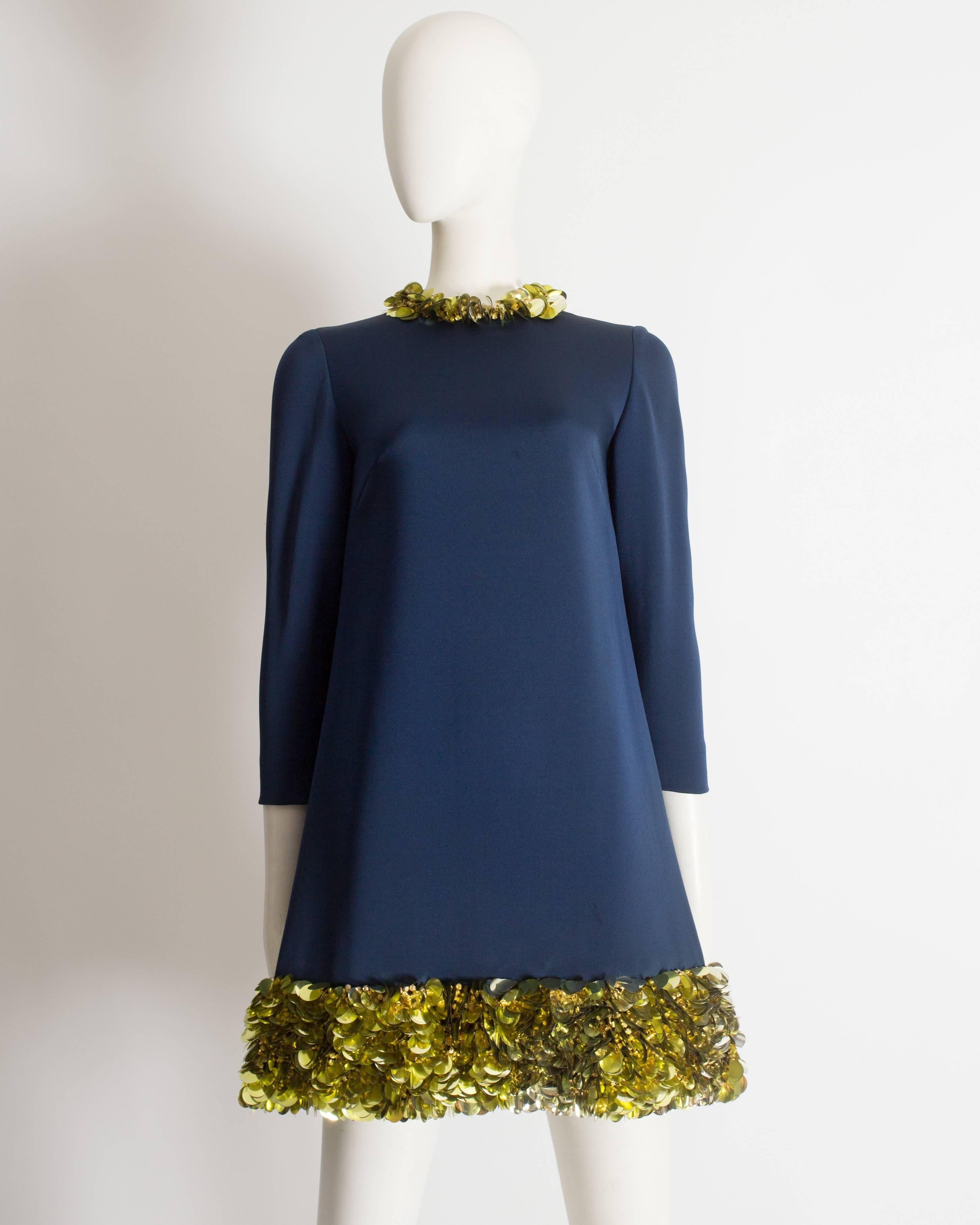 Wir präsentieren ein blaues Vintage-Seiden-Minikleid, ein wahrer Schatz an Opulenz und Glamour. Dieses exquisite Kleid ist mit goldenen, runden Spiegelscheiben und Perlen verziert, die dem Ensemble einen Hauch von Luxus und Raffinesse