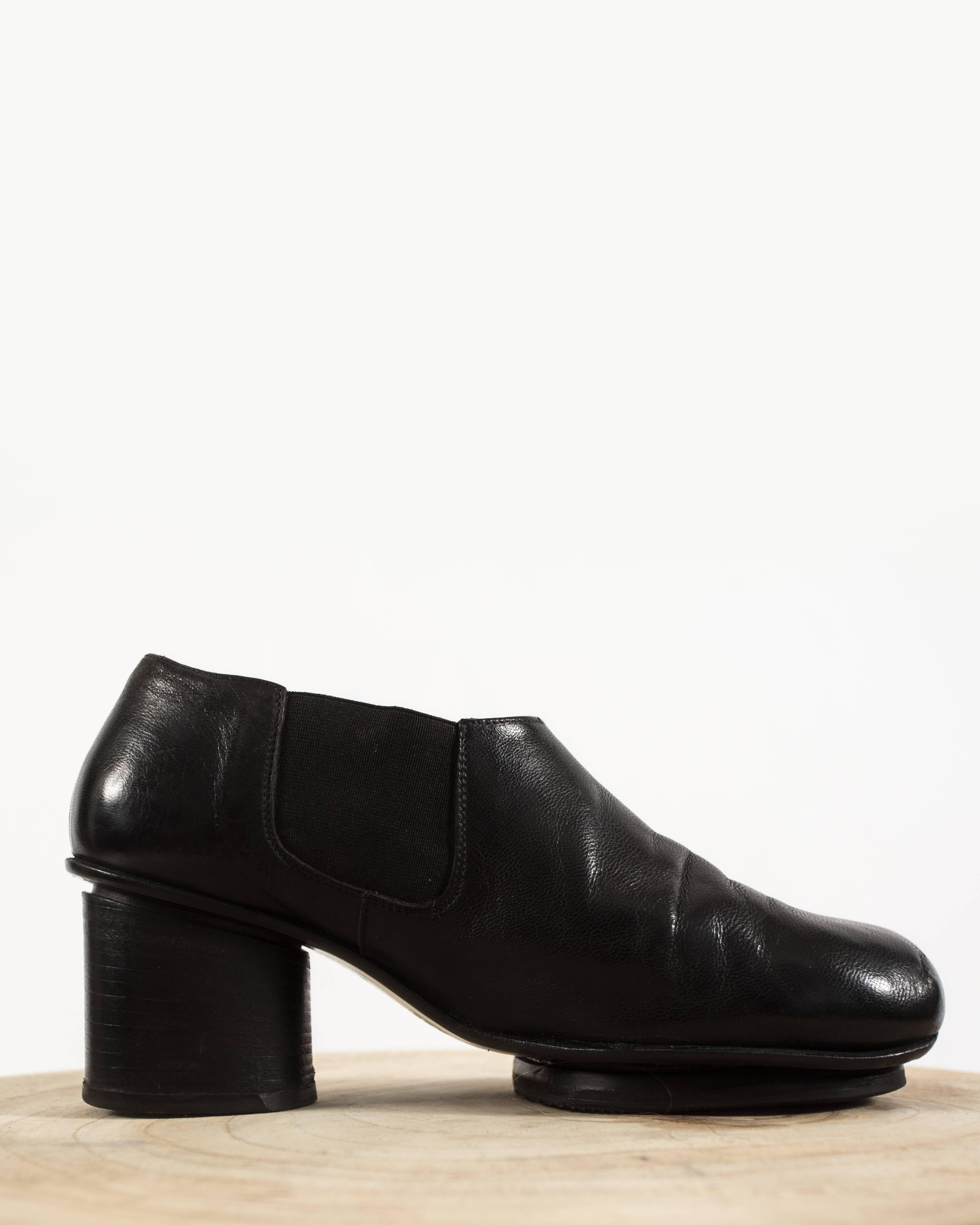Introducing the Martin Margiela Autumn-Winter 1999 shoes, a remarkable and innovative footwear creation from the avant-garde designer's iconic collection.

Crafted from luxurious black leather, these shoes feature round tips and a high oval stacked