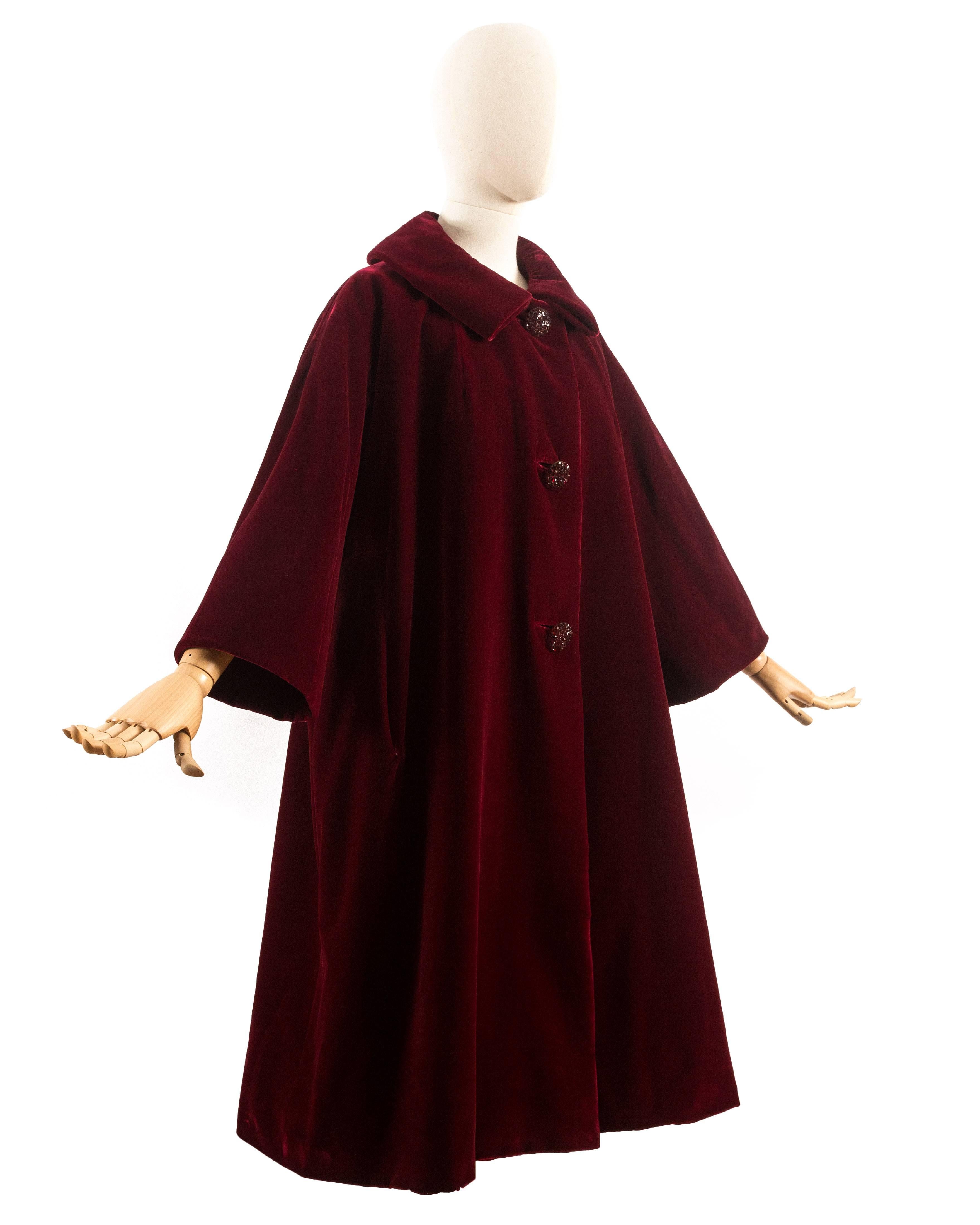 Christian Dior Haute Couture Autumn-Winter 1956 royal red silk velvet opera coat with three stoned button closures, Peter Pan collar, three-quarter length sleeves, and two hidden side pockets. 