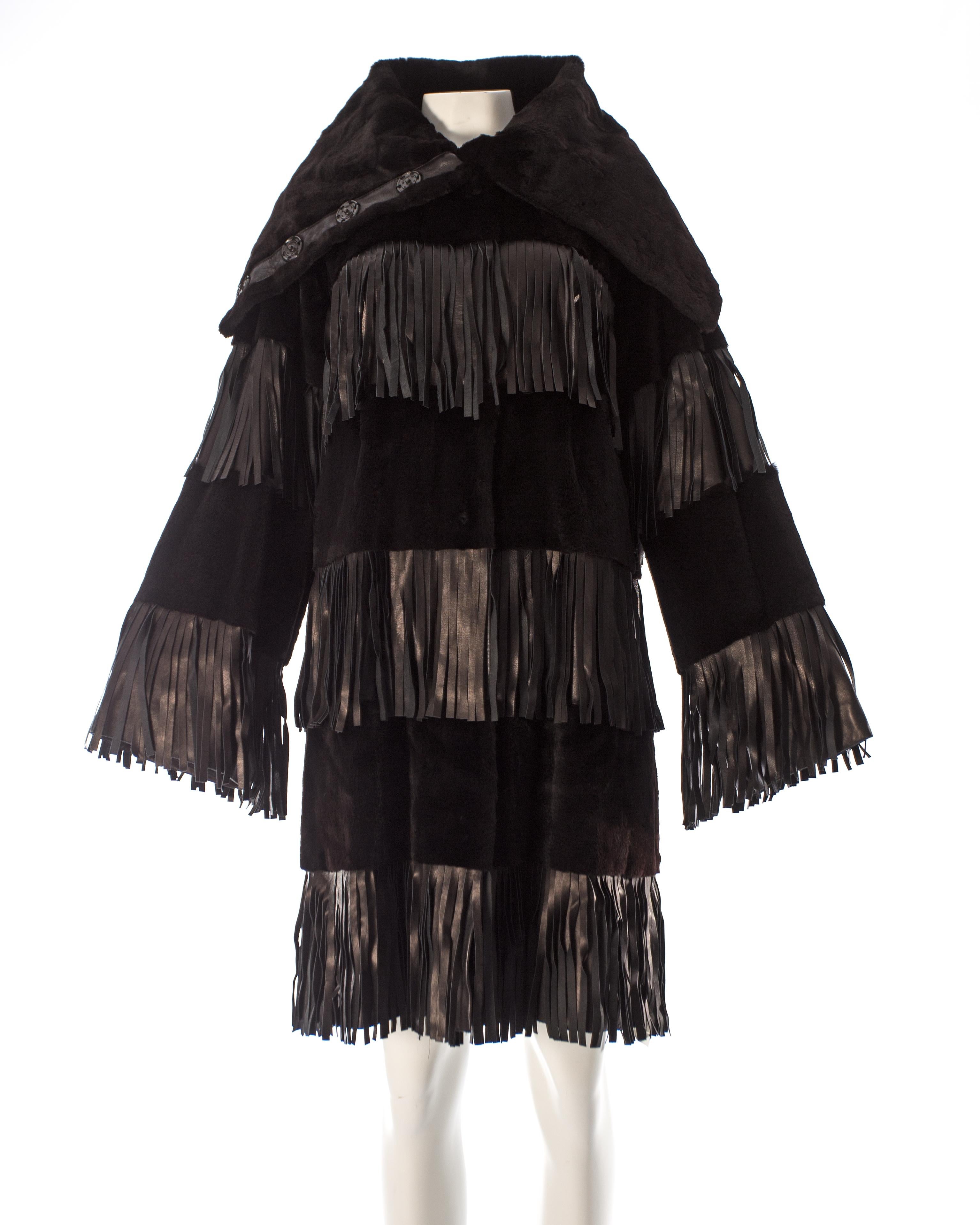Black sheared weasel fur coat with leather fringe inserts. 

- Extra tall funnel collar 
- Large snap button closures throughout 
- Black silk lining

Autumn-Winter 2003 