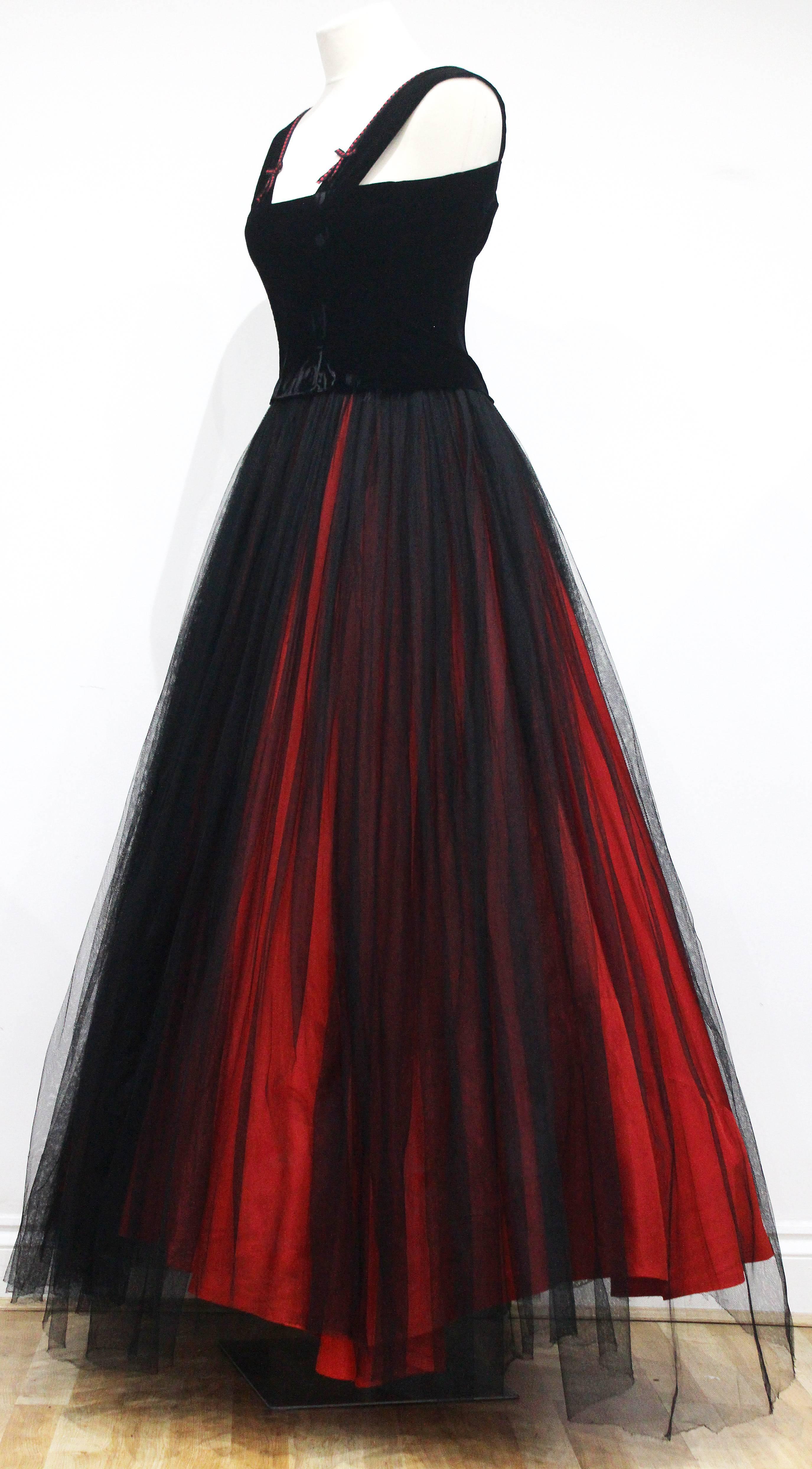 A fine and rare haute couture 1940s Jacques Fath evening skirt ensemble. The ensemble includes a velvet boned vest with hook and eye closure and a full black tulle skirt with a vibrant red silk underskirt. Judging by the label of this piece this