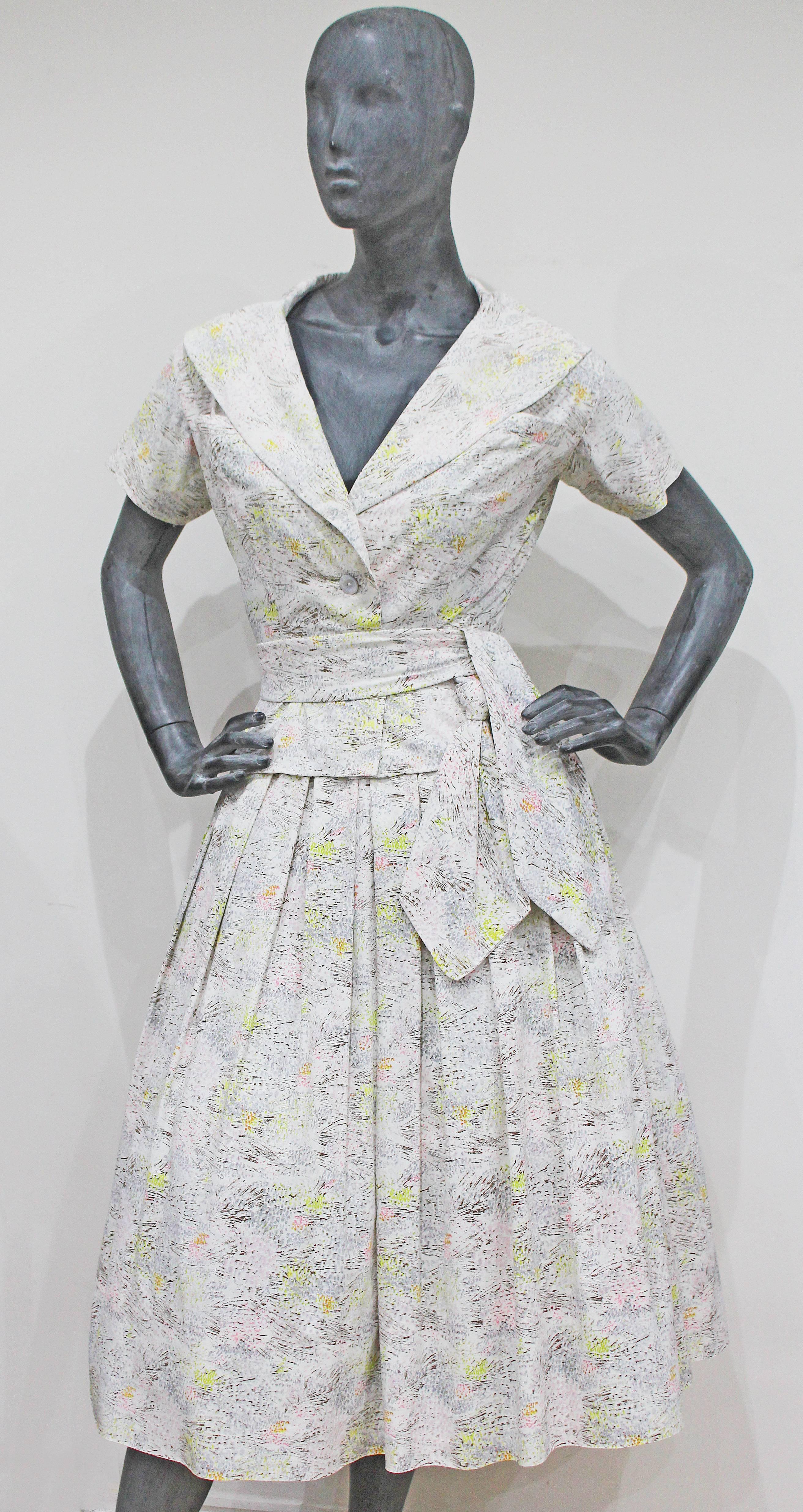An exceptional Christian Dior Haute Couture 'Lily of the Valley' silk dress suit from the Spring/Summer 1954 collection. The two piece suit consists of a short sleeved jacket a full pleated skirt and a waist belt. The jacket is cut in a classic Dior