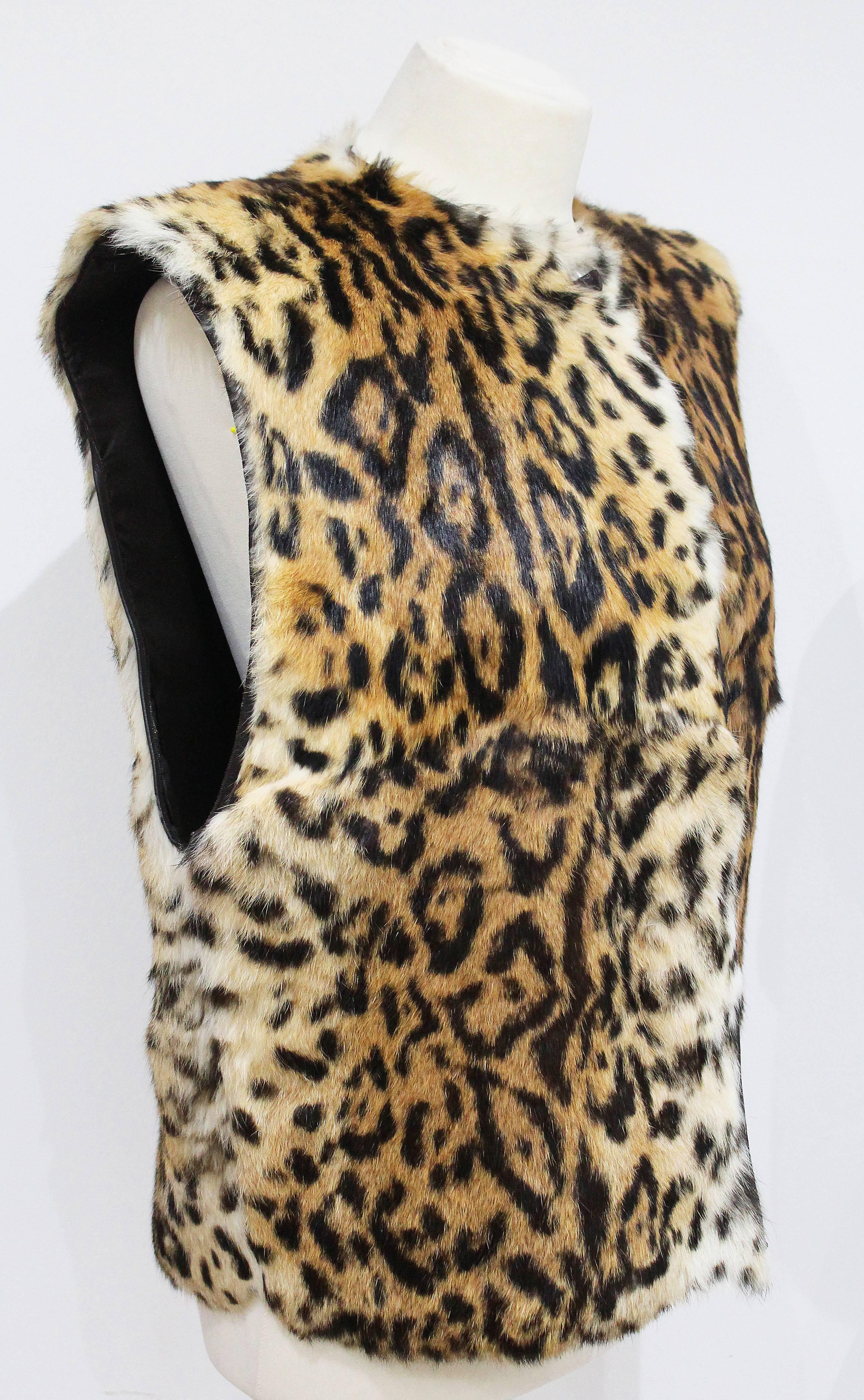 Il s'agit d'un gillet en fourrure de Gianni Versace, imprimé léopard, datant des années 1980. Le gillet est en fourrure de lapin douce et se ferme à l'aide de deux boutons en cuir. La coupe du gillet est très ample et surdimensionnée. 

Moyen/Large
