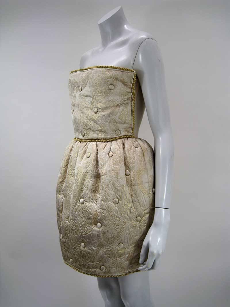 Outstanding gold Dolce & Gabbana quilted brocade dress.

Strapless with netted underlay and boning.

Gold cord trim.

Tufted skit that hits above knee.

Back zipper.

Skirt has satin lining.

Tagged a size 44.

Fabric of outer is polyester,