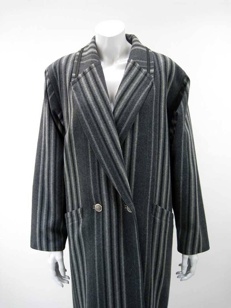 Handsome vintage Gianni Versace grey striped coat.

Oversize cut that narrows through hips.

Double-breasted with four two button closure.

Black ribbon trim on collar and back belt.

Front slant pockets on hip.

Wool with nylon lining. 

The coat