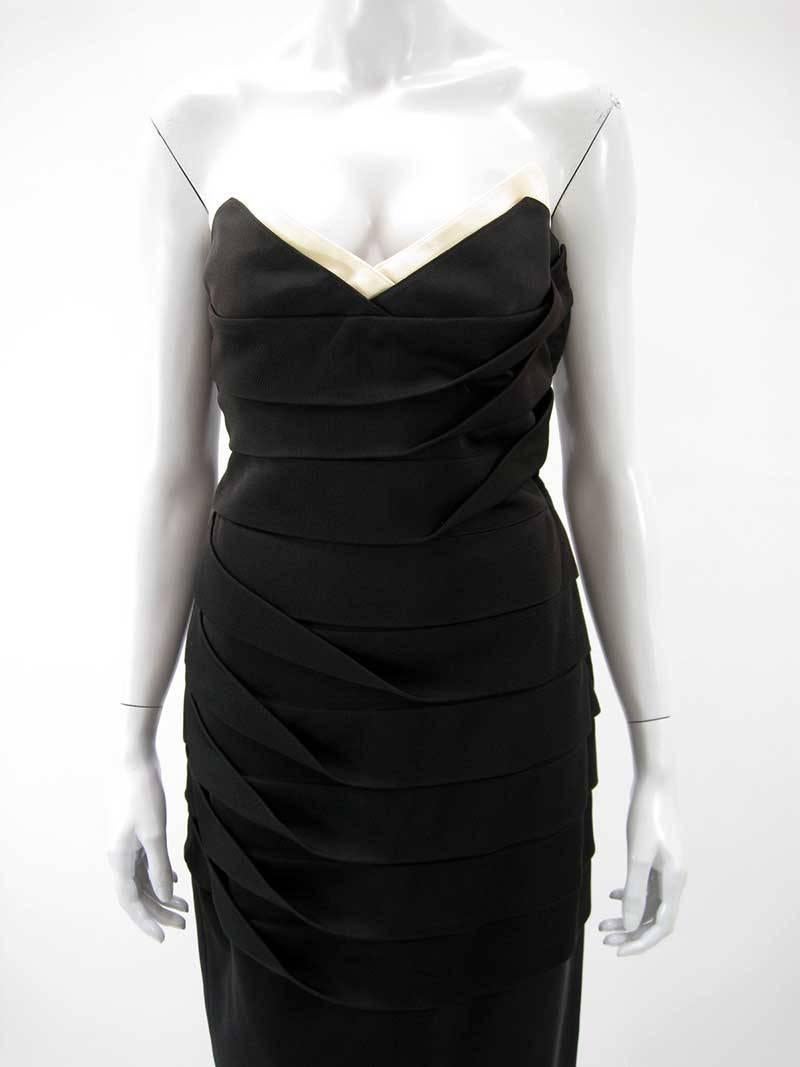 Fabelhaftes schwarzes trägerloses Kleid von Gianni Versace.

Umklappbarer Kragen in Off-White.

Stärkeres Stretch-Trikot.

Durch das Mieder verlaufende Falten sorgen für eine figurbetonte Form.

Seitlicher Reißverschluss. 

Der Stoff ist eine
