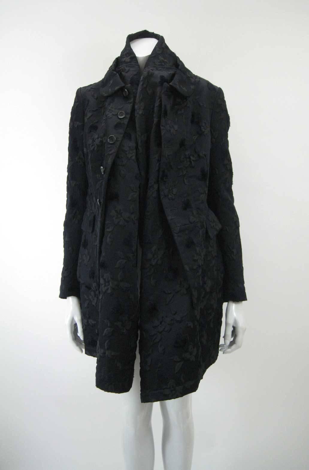 Avant garde Comme des Garcons black brocade coat.

The coat features an exaggerated partially attached lining tucks in and creates an added layer around neck and head and down body.

Outer rounded fold over peter pan style collar.

Five button