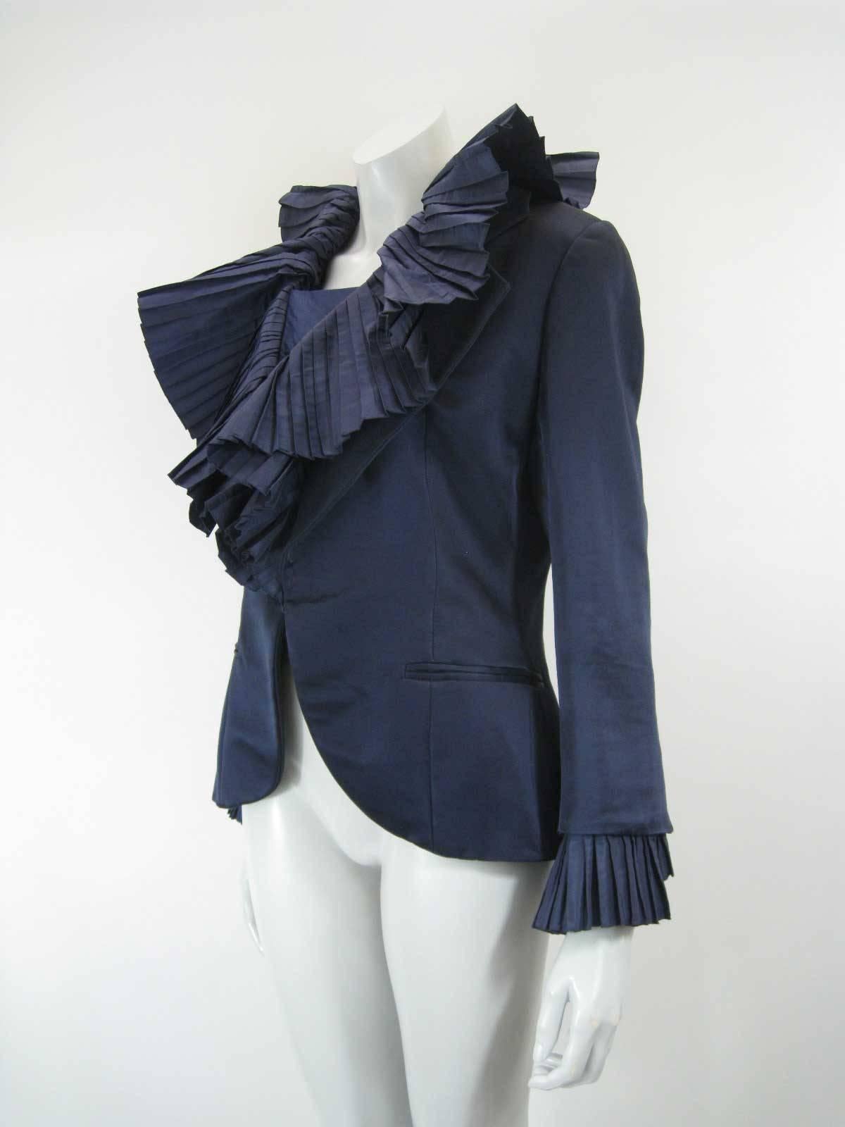 Stunning vintage Christian Dior Boutique evening jacket.

Deep blue satin color. 

Exaggerated accordian pleated collar and cuffs.

Hidden snap closure.

Hidden button placket.

Faux pockets on front hip.

Button cuffs.

Numbered 45148. Handwritten