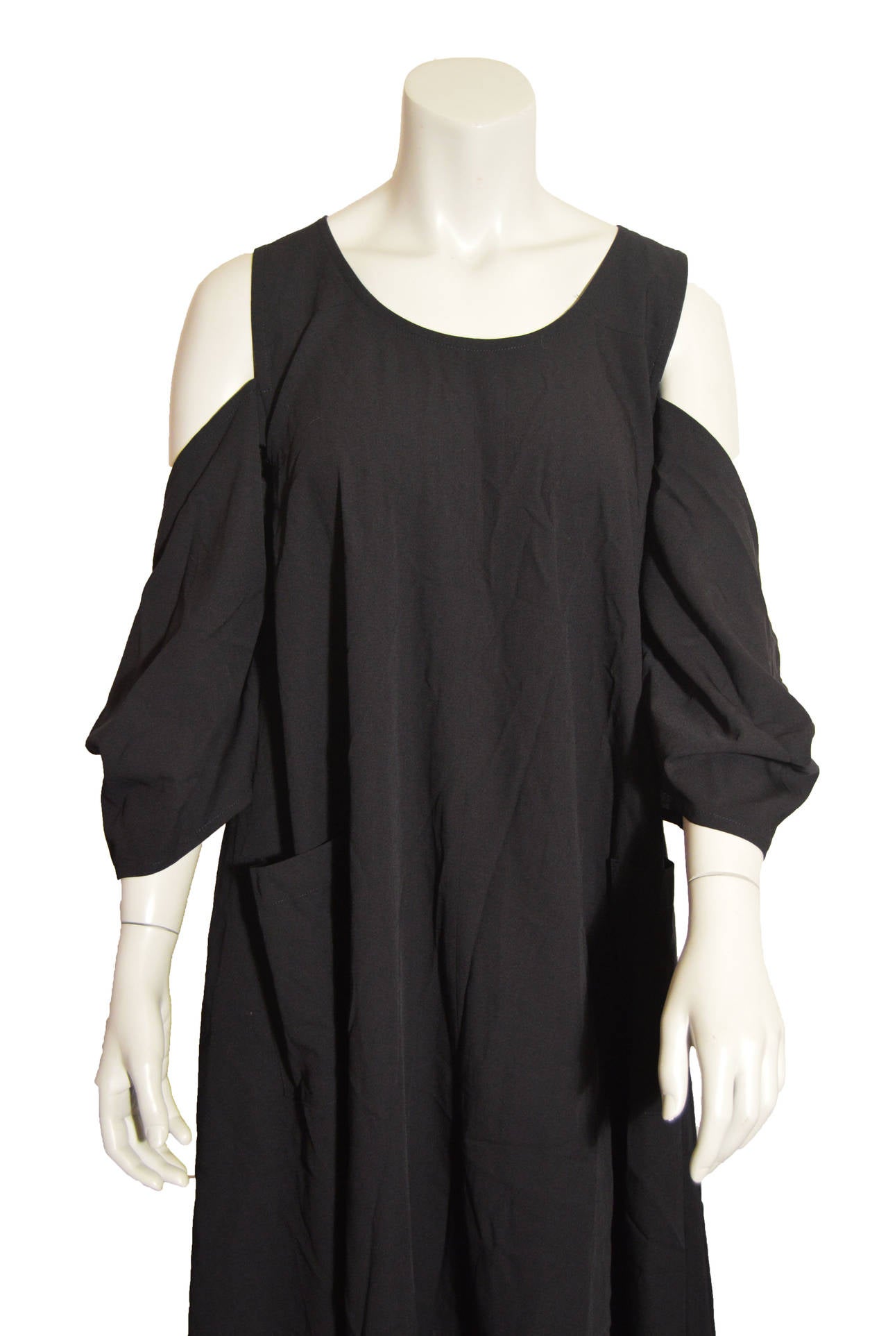 This elegant Yohji Yamamoto dress in black wool and nylon is beautifully designed. The shoulder cutouts, scoop neck and rectangular sleeves exemplify Yamamoto's avant-garde stylings. The dress is tagged a size small.