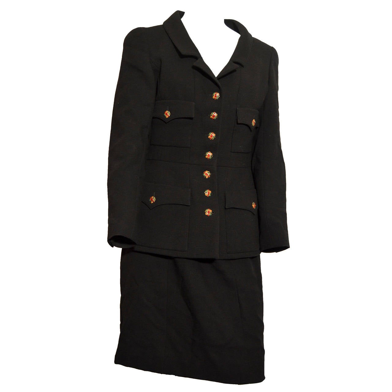 This black wool suit from Chanel has a notched collar, Princess seams and elegant Gripoix buttons. There are 4 front pockets with arched covers and 3-button cuffs. The suit is tagged a size 42.