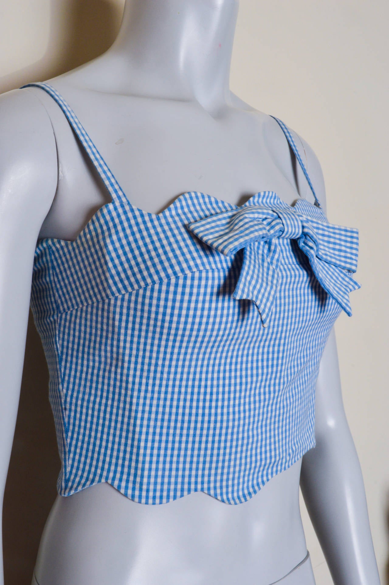Pale blue and white gingham check fitted top.
Scalloped neckline with bow.
Boning in liner for shape.
Darted bust. 
Spaghetti straps.
Back zipper.
Stretch.
Tagged a US size 6.