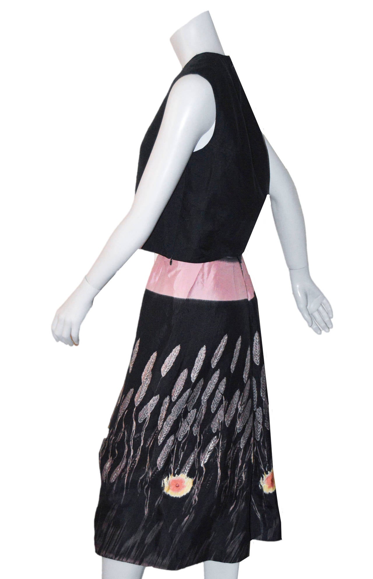 Elegant Miuccia Prada two piece ensemble.
Simple black sleeveless top with printed A-line skirt.
The top features darting and back zipper.
Wide pale pink waist band with cattail and floral print.
Pintucked pleats detailing on hip.
Snap
