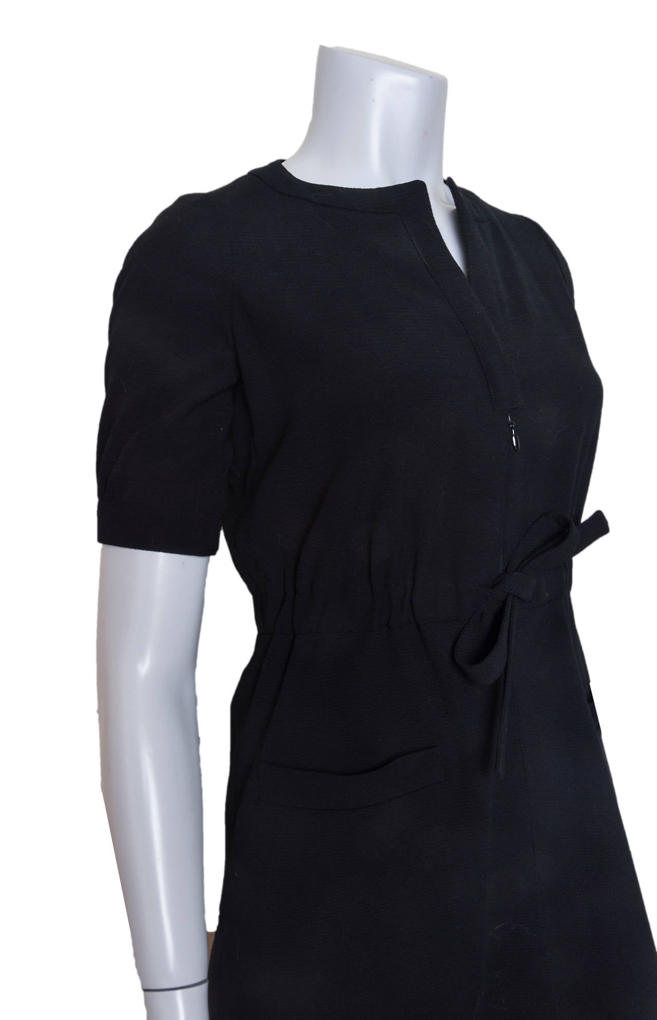 Classic black dress by Courreges Hyperbole.
Constructed, heavier weight fabric gives shape.
Stretch waistband with tie.
Banded short sleeves.
A-line skirt with pockets.
Fully lined.