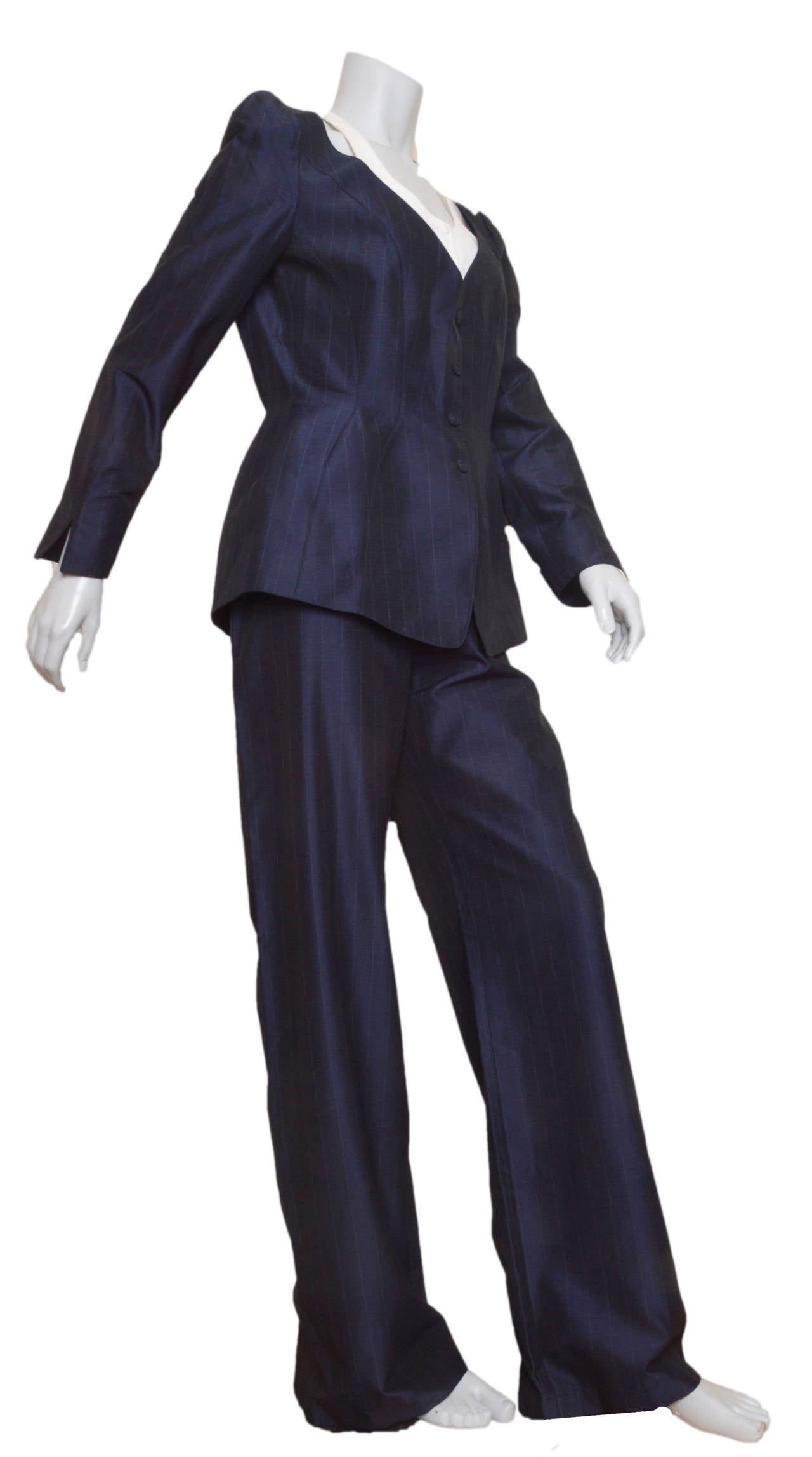 Incredible and iconic Thierry Mugler pant suit.
Navy blue with white pin striping. Fabric has slight sheen.
Jacket has hidden snap closures with faux fabric buttons.
Hourglass shape/seaming and side slit pockets on hip.
Built in white bib/vest