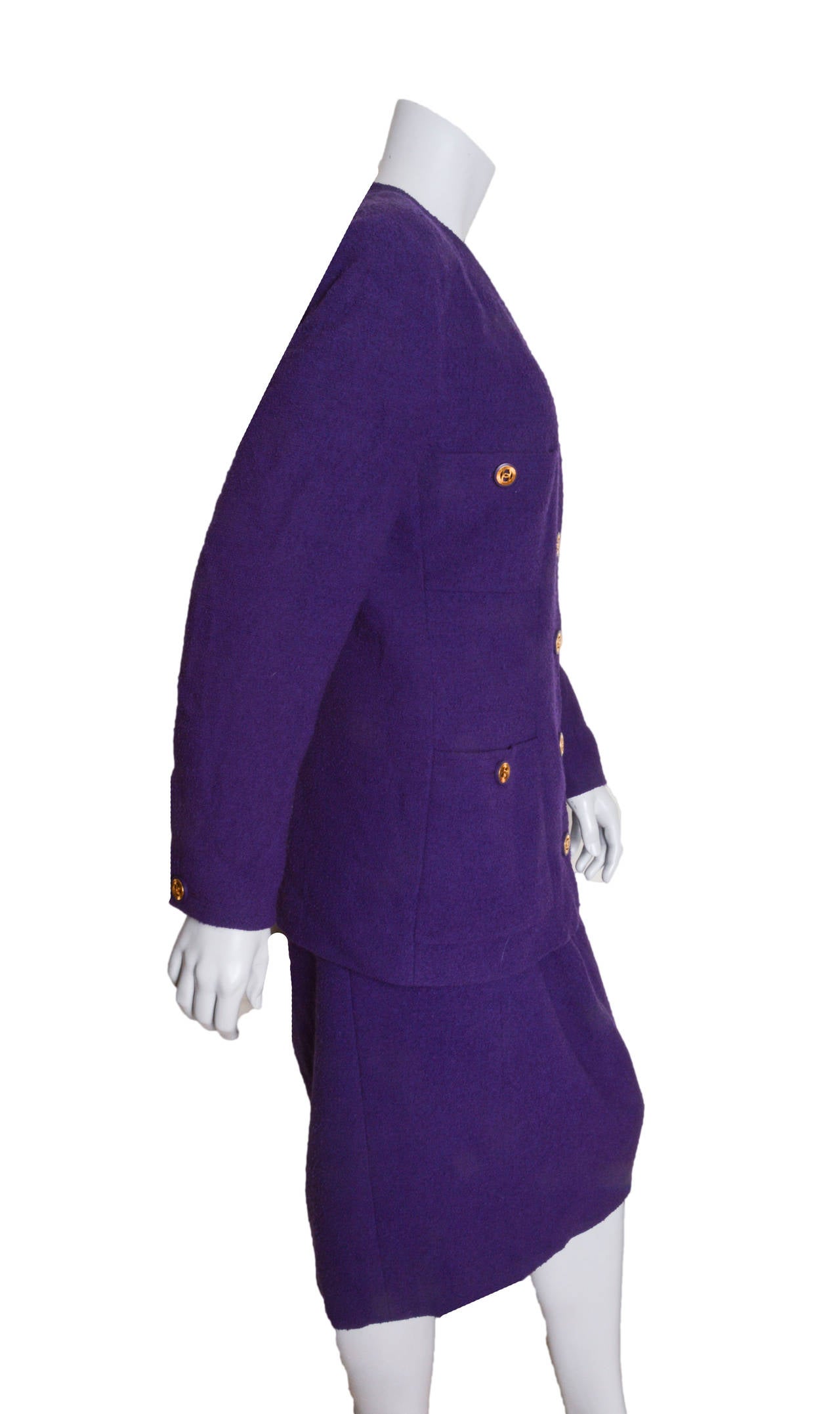 Iconic vintage Chanel Boutique purple boucle skirt suit.
Gorgeous vibrant purple wool nylon blend.
Lined in silk throughout.

Handwritten on tag:
Collection: 26
Style: 20919
Size 44

Jacket features classic four pockets.
Cc logo embossed