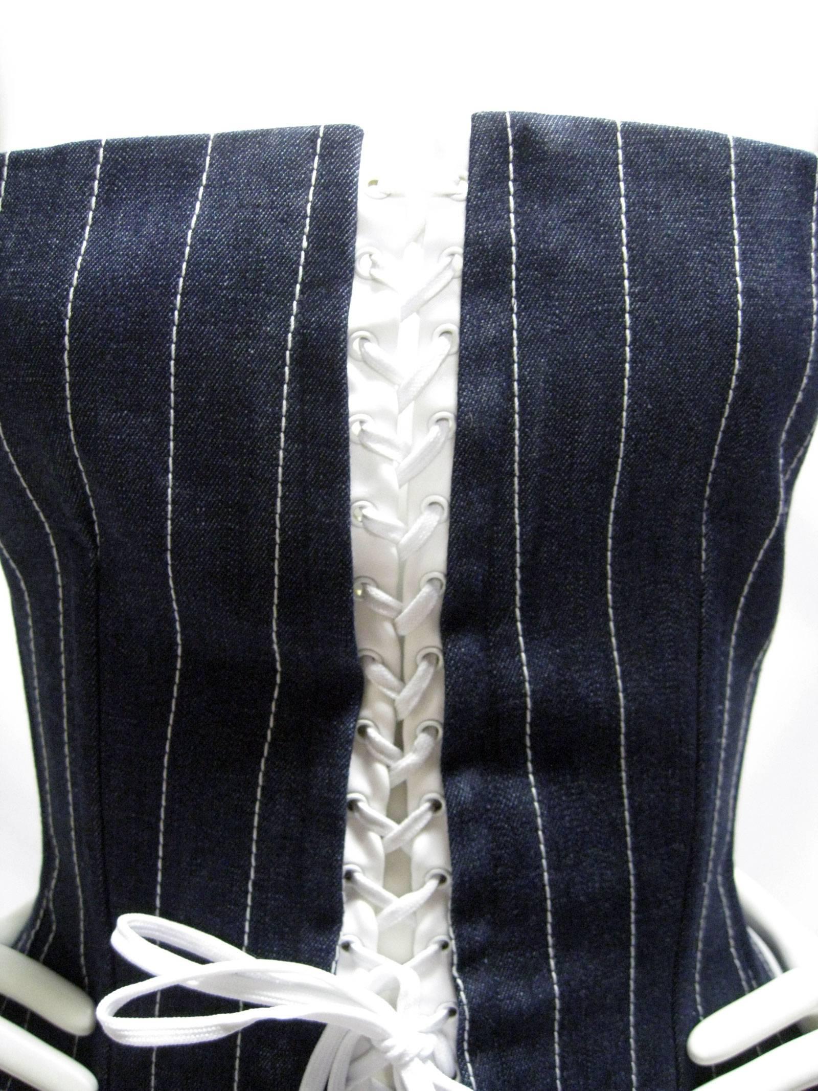 Dolce & Gabbana dark denim corset.
Circa 1990s.
Very dark blue, raw denim. 
White stitching pin stripes.
White stretchy laces with grommeted holes.
Side boning, substantial weight and structure.
Lower hip area is padded around the back and hip