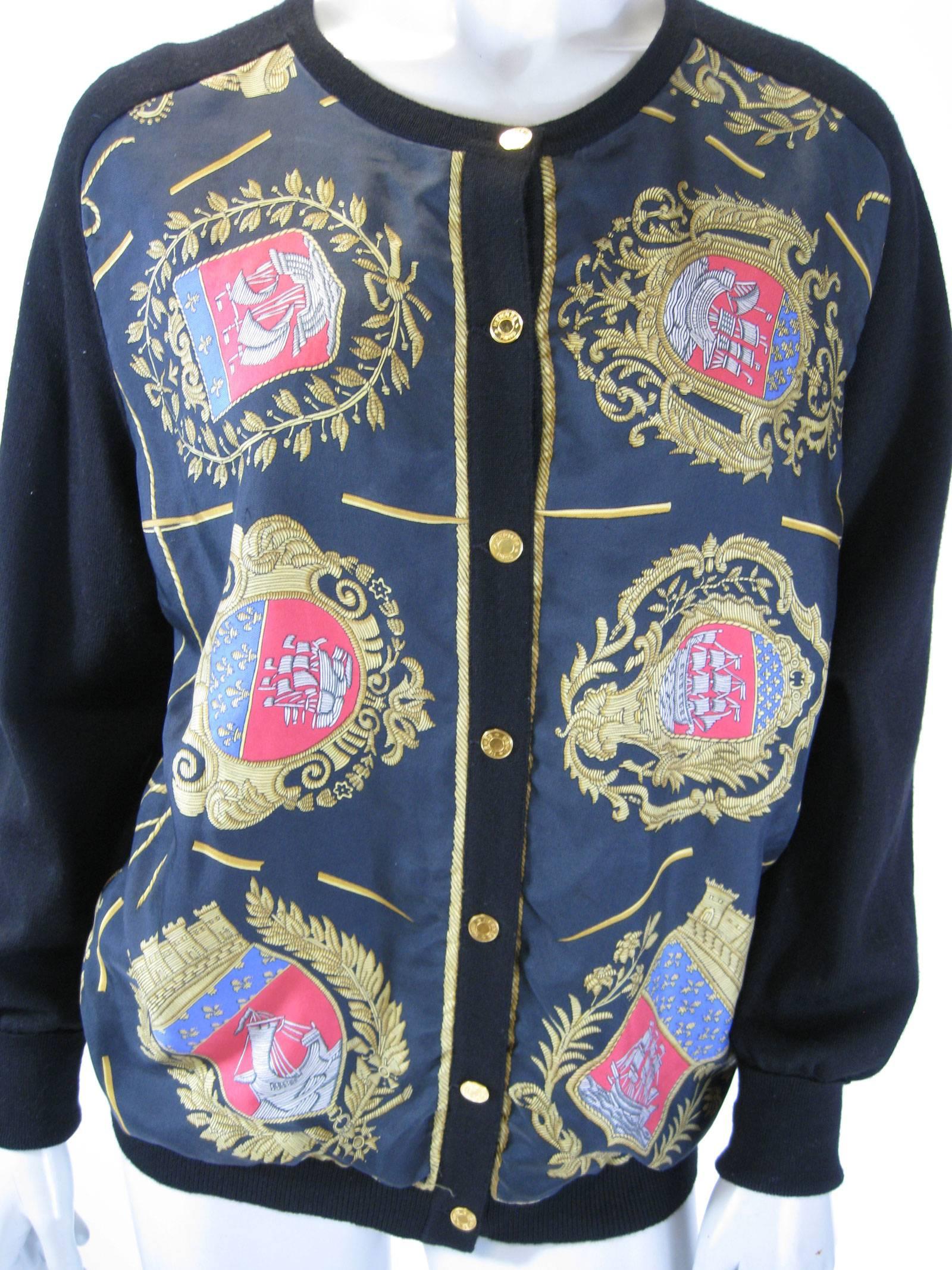 Vintage Hermes black silk and wool cardigan.
Front silk panels, wool arms and back.
Striking gold, blue and red emblems featuring wooden ships.
Hermes stamped gold buttons.
Unlined.
Tagged a size 44.

Bust: 44