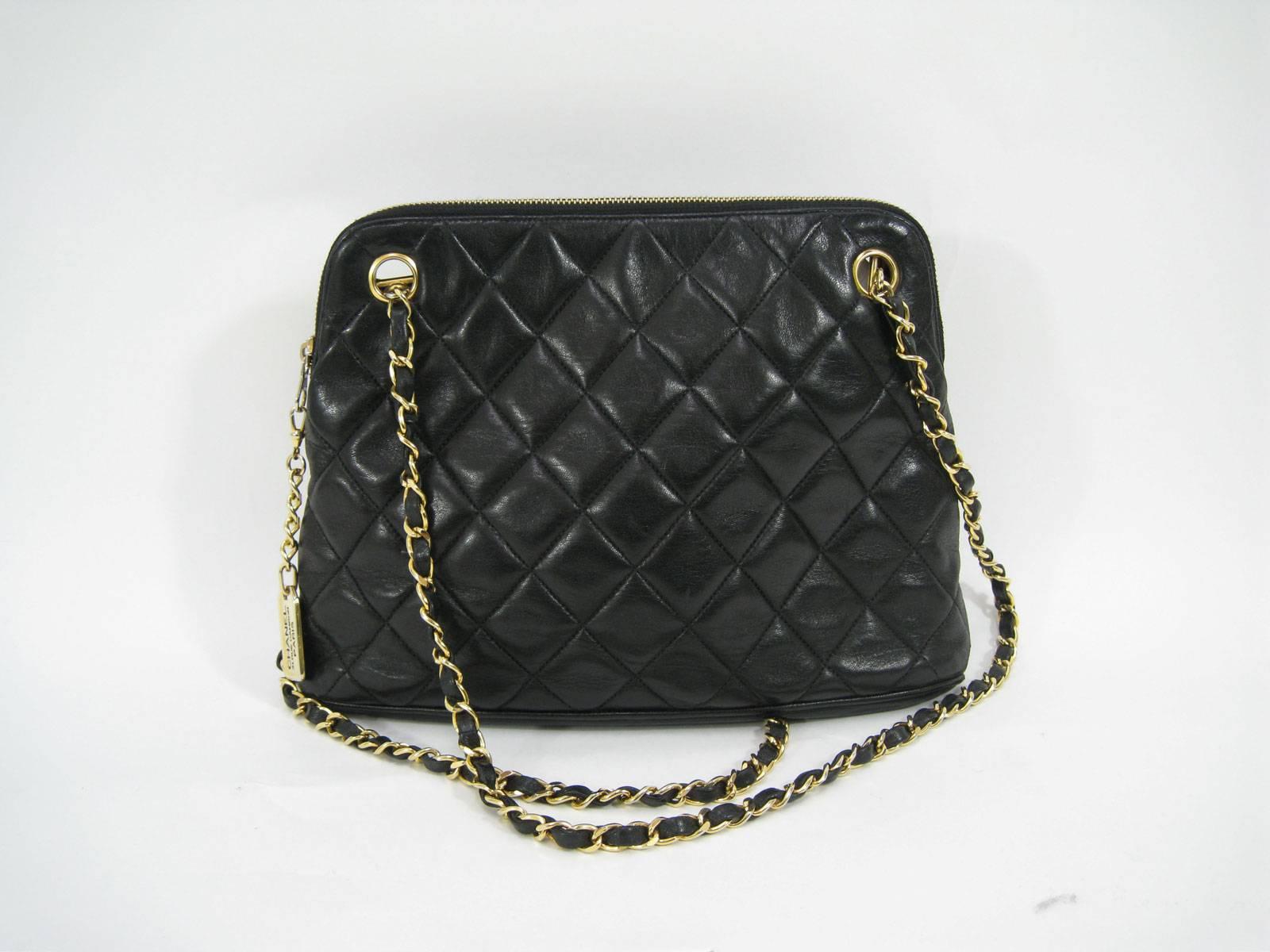 Supple black lambskin Chanel handbag.
Gold hardware throughout.
Two gold and leather chain straps.
Two inside pockets.
Serial number found inside one pocket: 1078699
Top zipper with Cc pull tab.

Measurements:
Width: 12