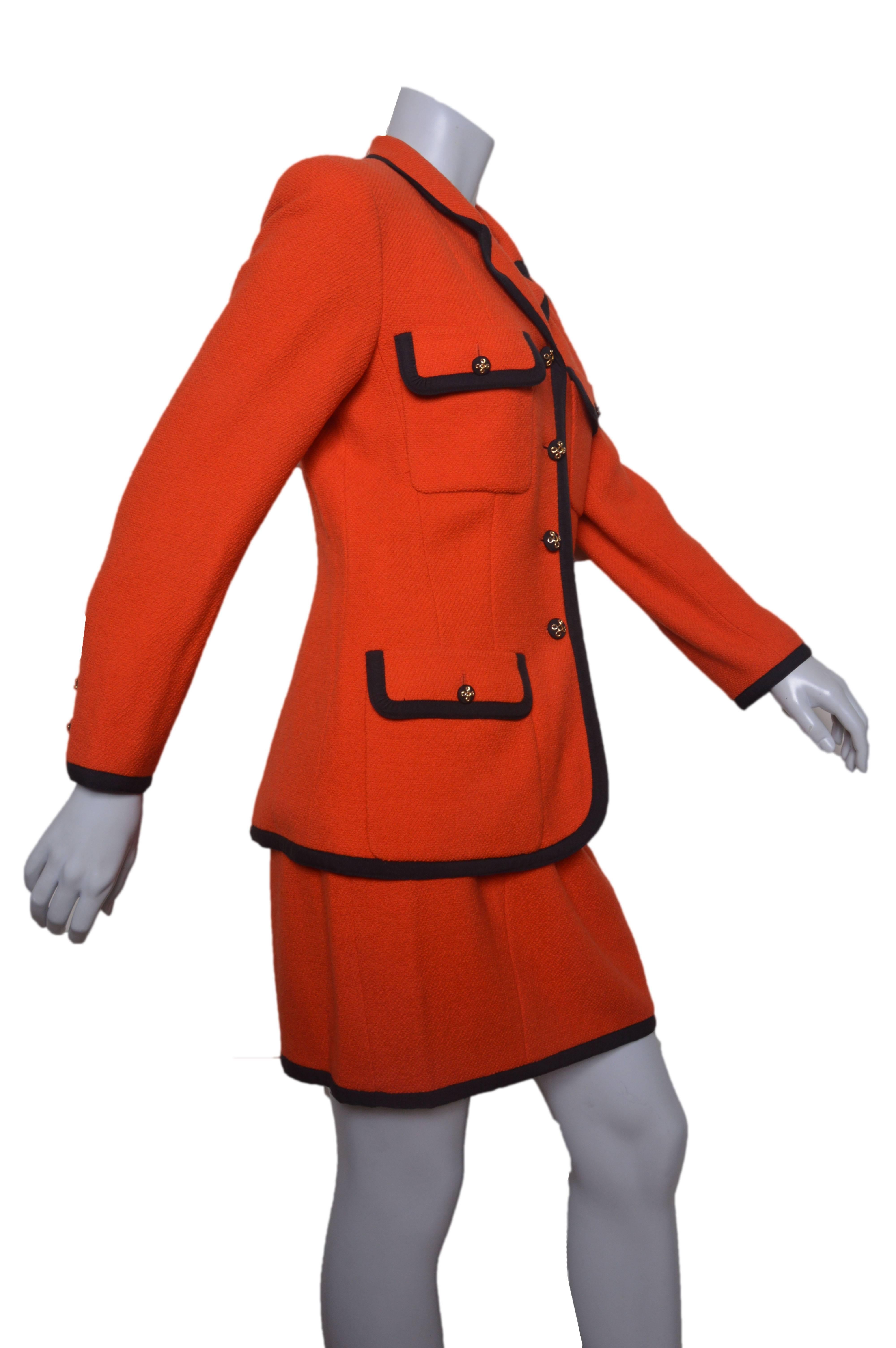 Vintage bright orange Chanel Boutique suit.
Orange wool black with black ribbon trim.
Iconic details on jacket.
Two chest pockets and two hip flap pockets.
Slightly fitted shape.
Gold buttons throughout and of cuffs.
Skirt is straight with