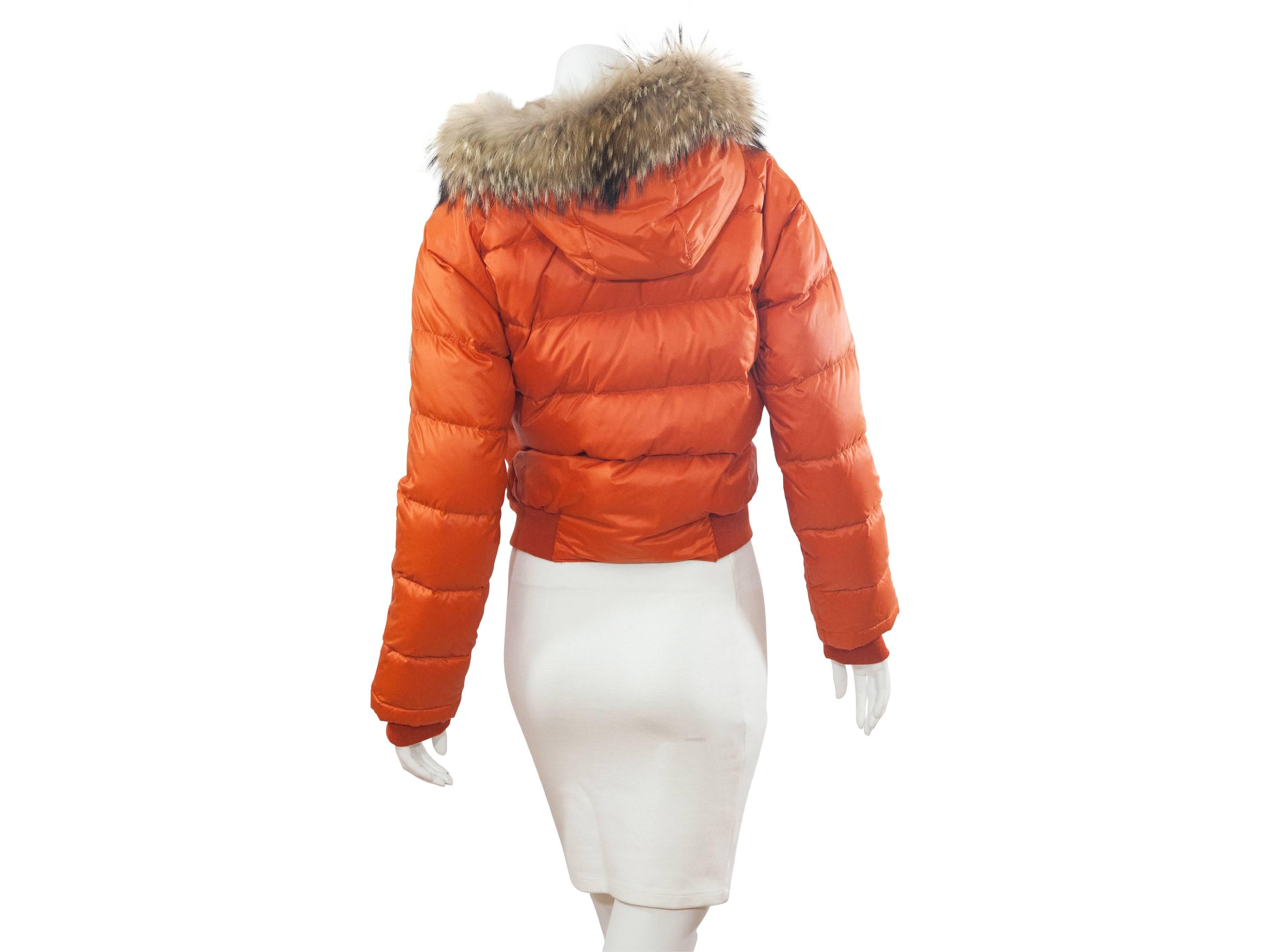 Orange quilted down jacket by Moncler.  Rabbit and fox fur trimmed hood.  Button closure over zip front.  Snap-close slide pockets. 