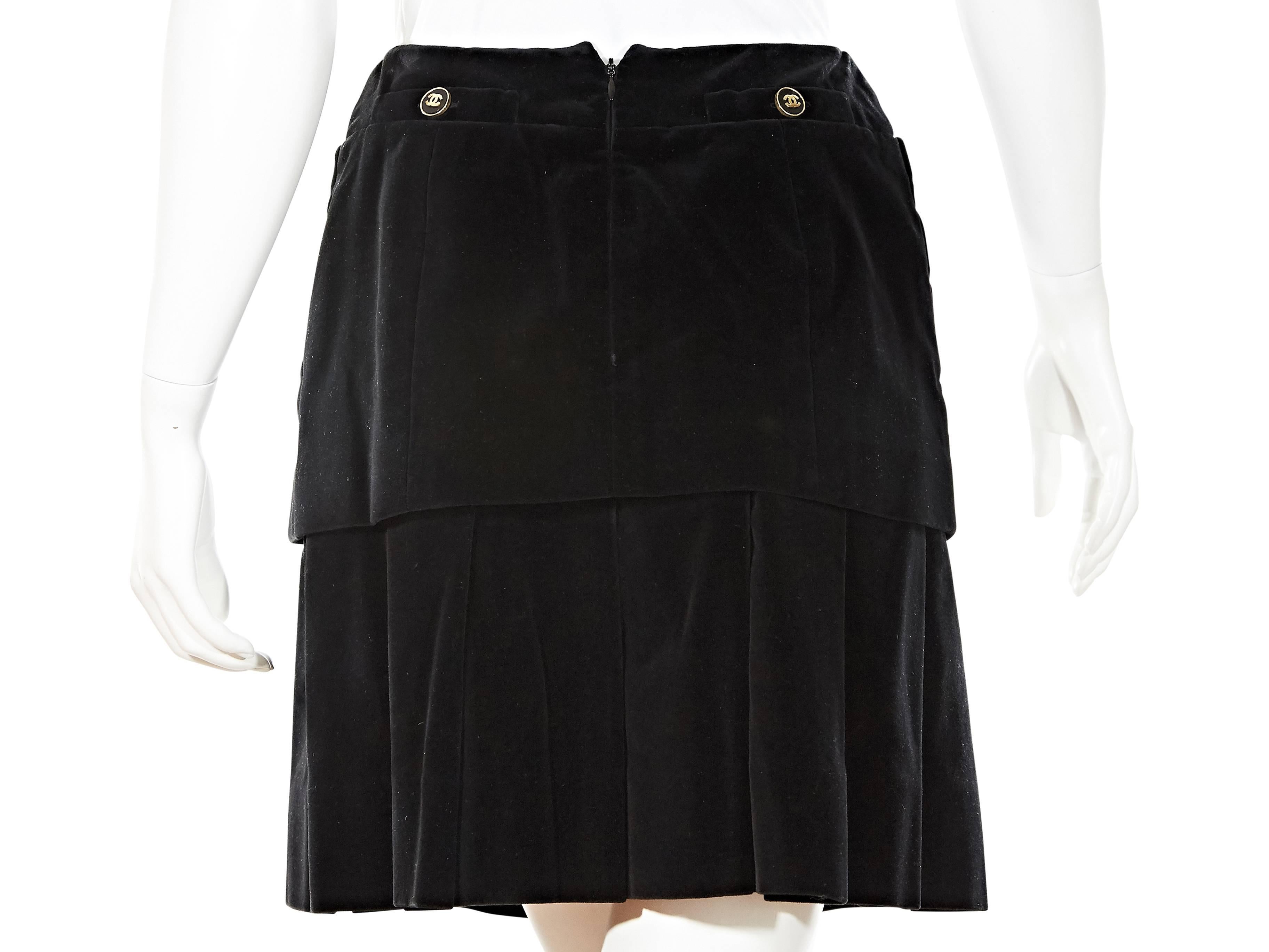 Black velvet skirt by Chanel. Tiered design with box pleated hem.  Front patch and back button pockets. Concealed back zip closure. 

Sizing converted to US size for New York based store purposes.