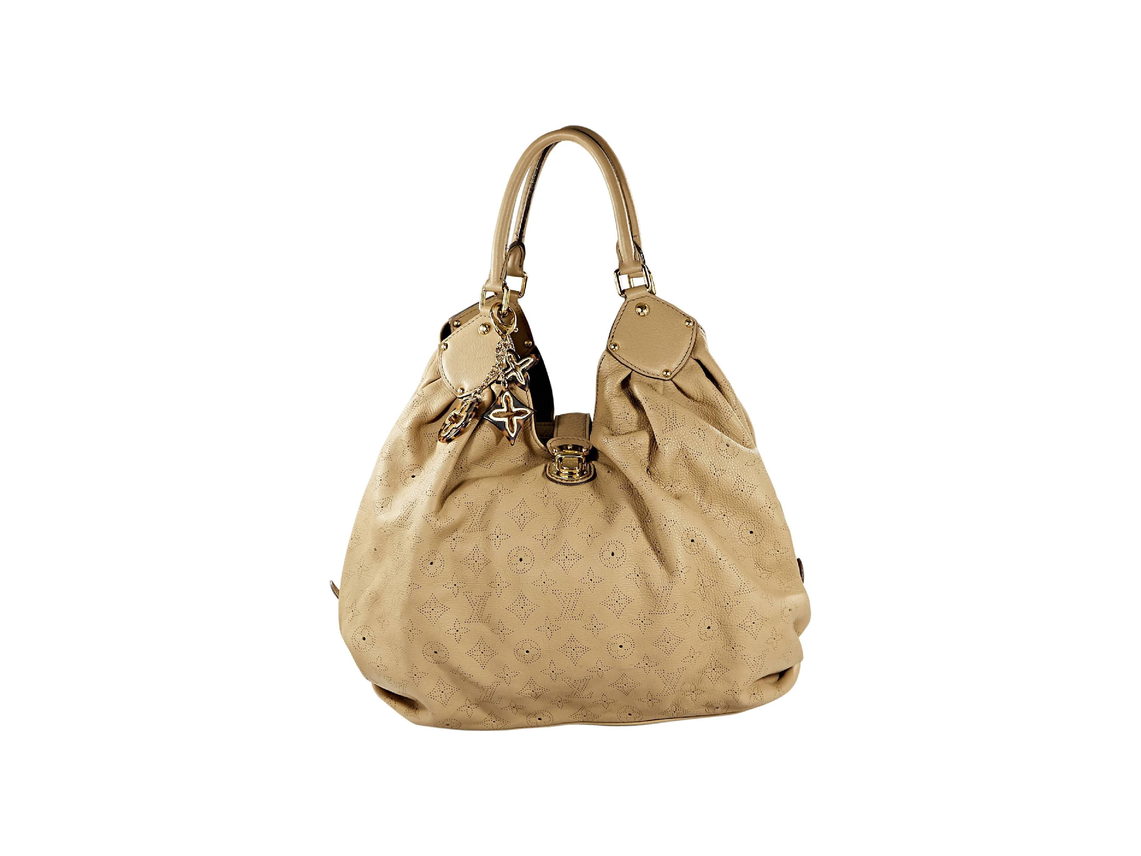 Tan mahina leather XL hobo bag by Louis Vuitton.  Perforated monogram design.  Hanging charm accents.  Double shoulder straps.  Top pushlock strap closure.  Protective metal feet.  Goldtone hardware.  