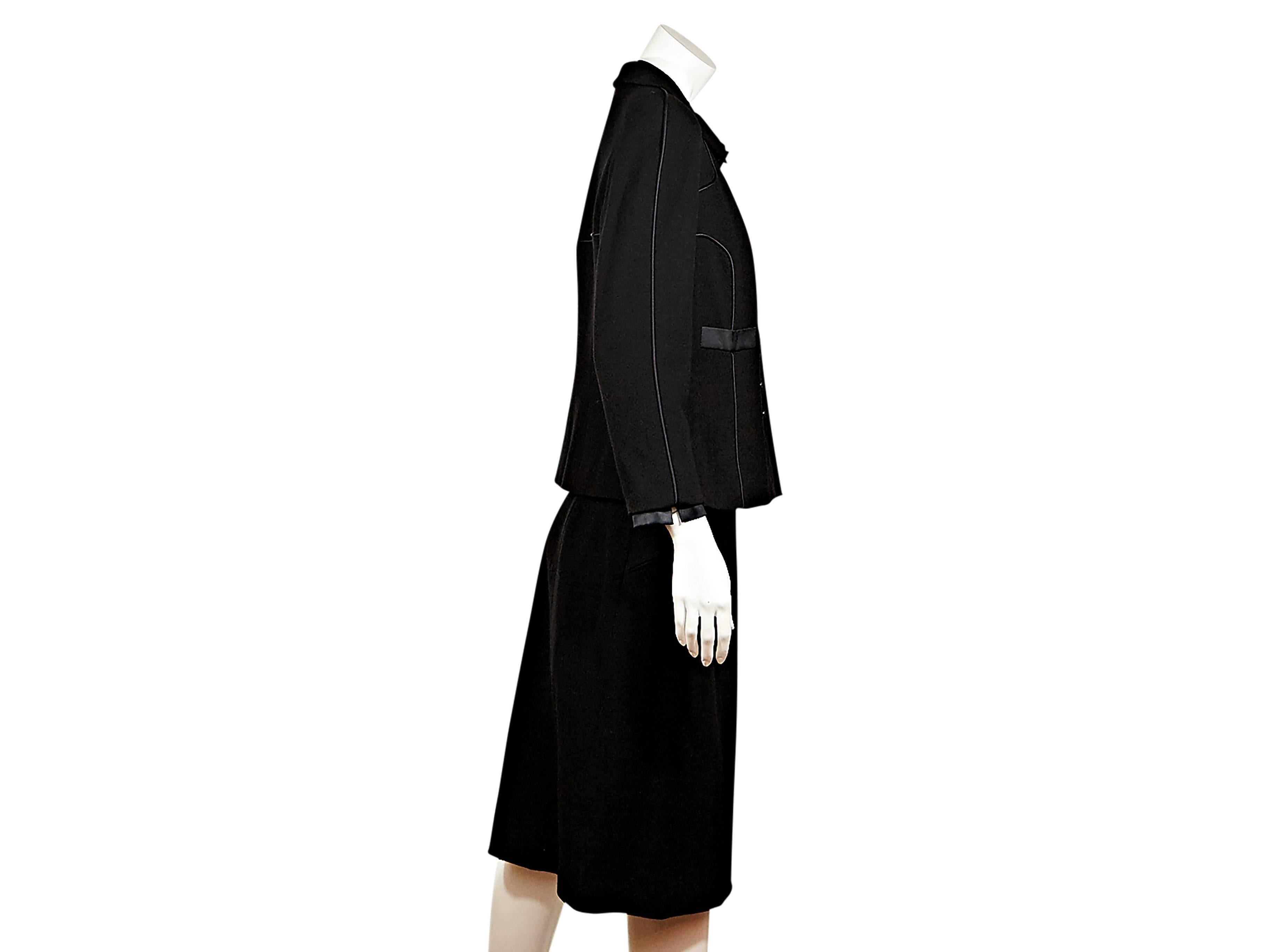 Product details: Black skirt suit set by Chanel.  Black wool jacket with silk trim.  Button-front closure.  Matching black pencil skirt.  Diagonal zip pockets. 

French sizing converted to US sizing at New York store.