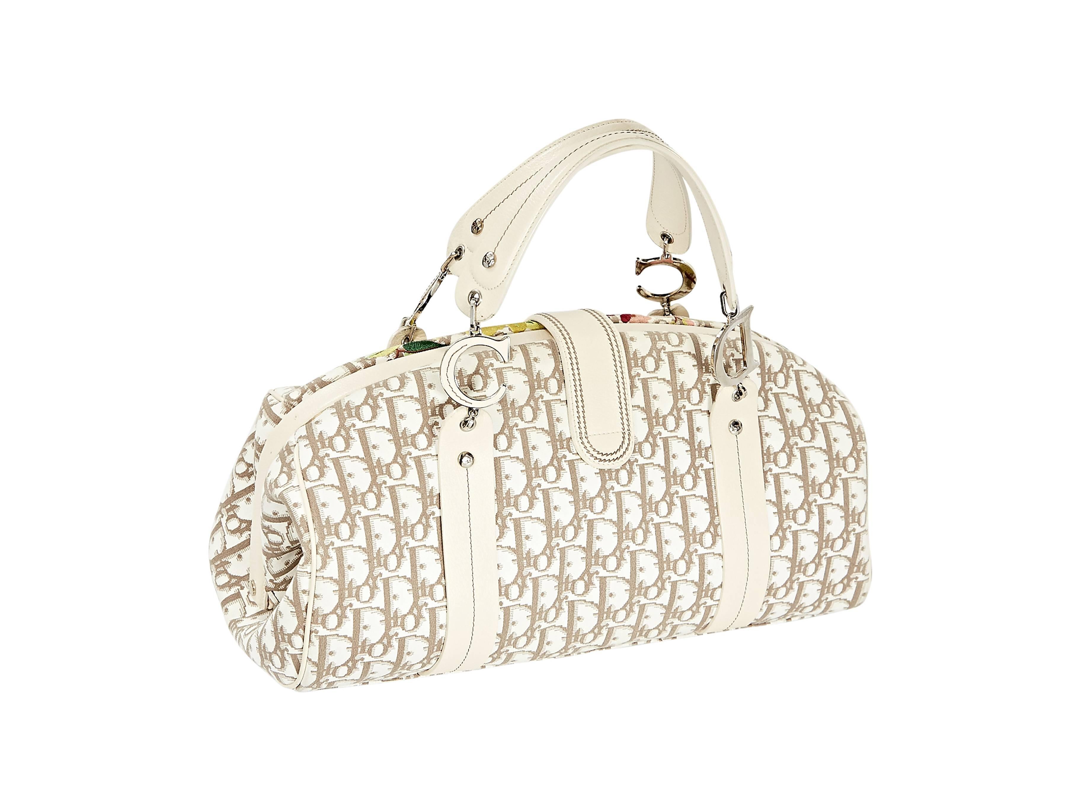 Brown and white monogram bag by Christian Dior.  Accented with multicolor floral embroidery. Top buckle strap closure.  Lined interior with zip and slide pockets.  Protective metal feet.  Silvertone hardware.  