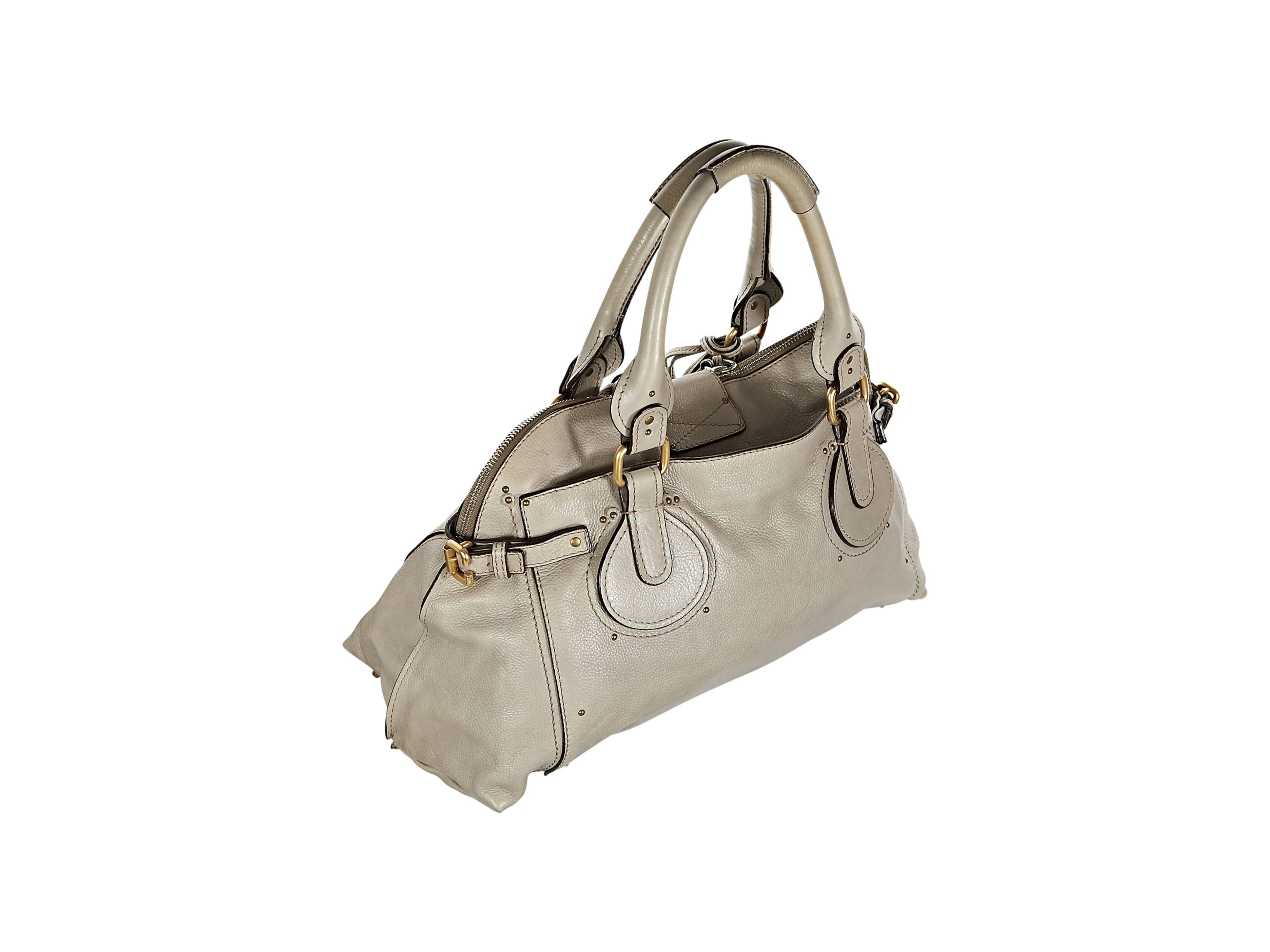 Taupe leather Paddington tote bag by Chloe.  Studded details.  Dual carry handles.  Lock and key closure on zip-close front flap.  Side buckle accents.  Back exterior slide pocket.  Protective metal feet.  Goldtone hardware.
