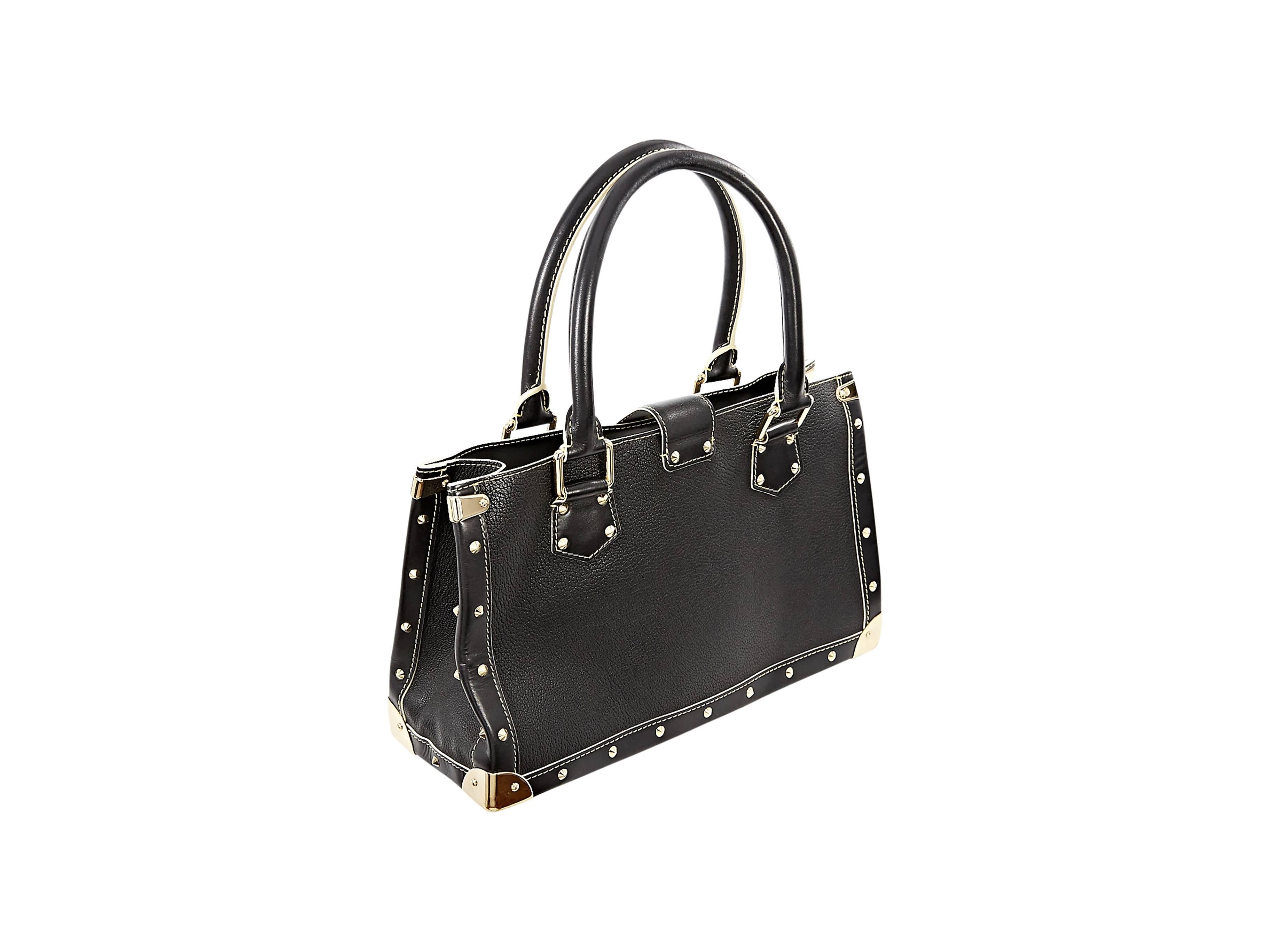 Black leather tote bag trimmed with studs by Louis Vuitton.  Dual carry handles.  Top buckle strap with lock and key closure.  Front zip pocket.  Lined interior with two inner compartments. Inner zip divider pocket and open pockets.  Goldtone