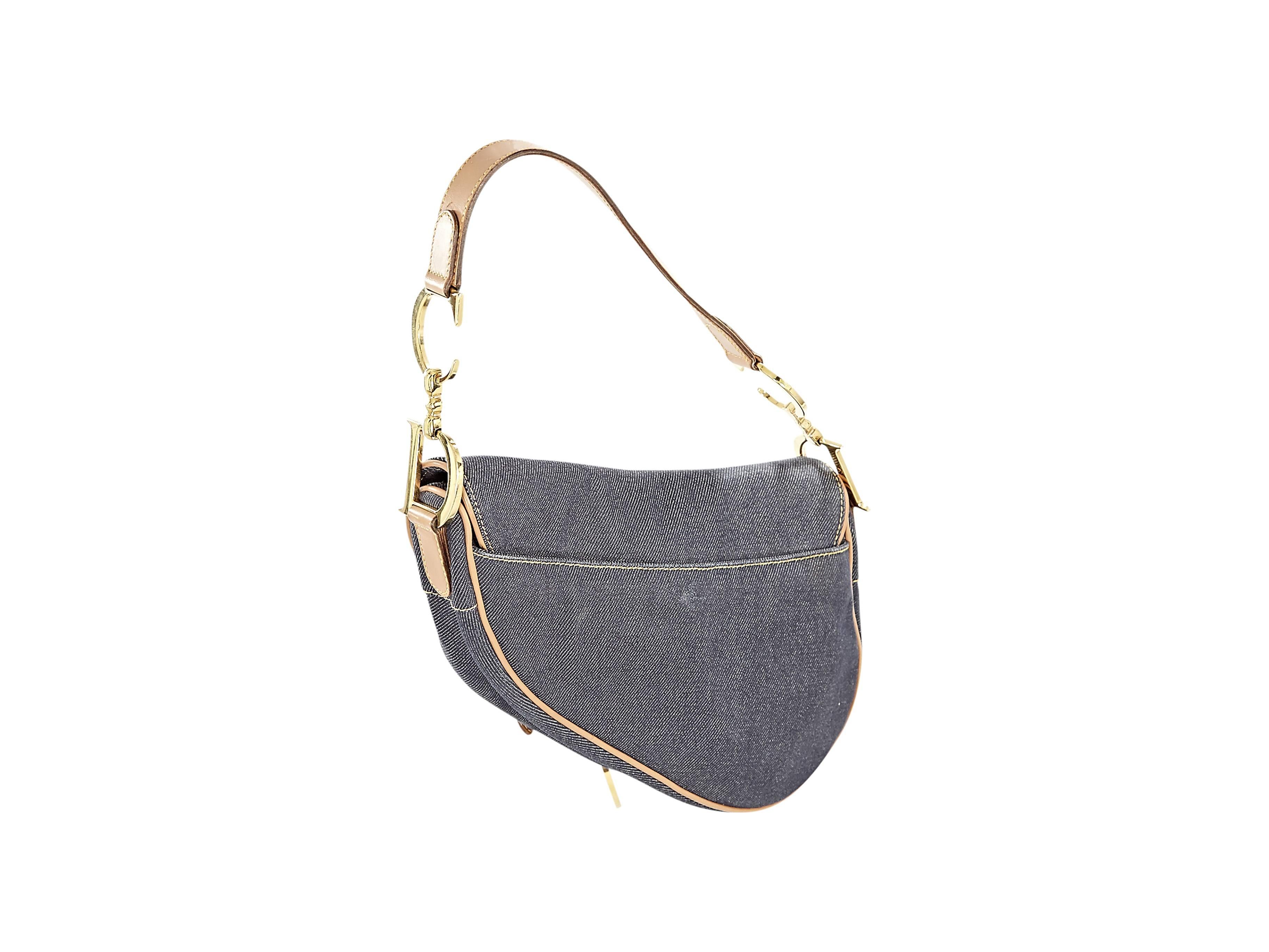 Blue denim saddle bag by Christian Dior.  Features tan leather trim.  Single shoulder strap.  Front flap with hanging 'D' charm.  Lined interior with inner zip pocket.  Goldtone hardware. Shoulder Strap Drop 7”, Height 6”, Width 9”, Depth 1”