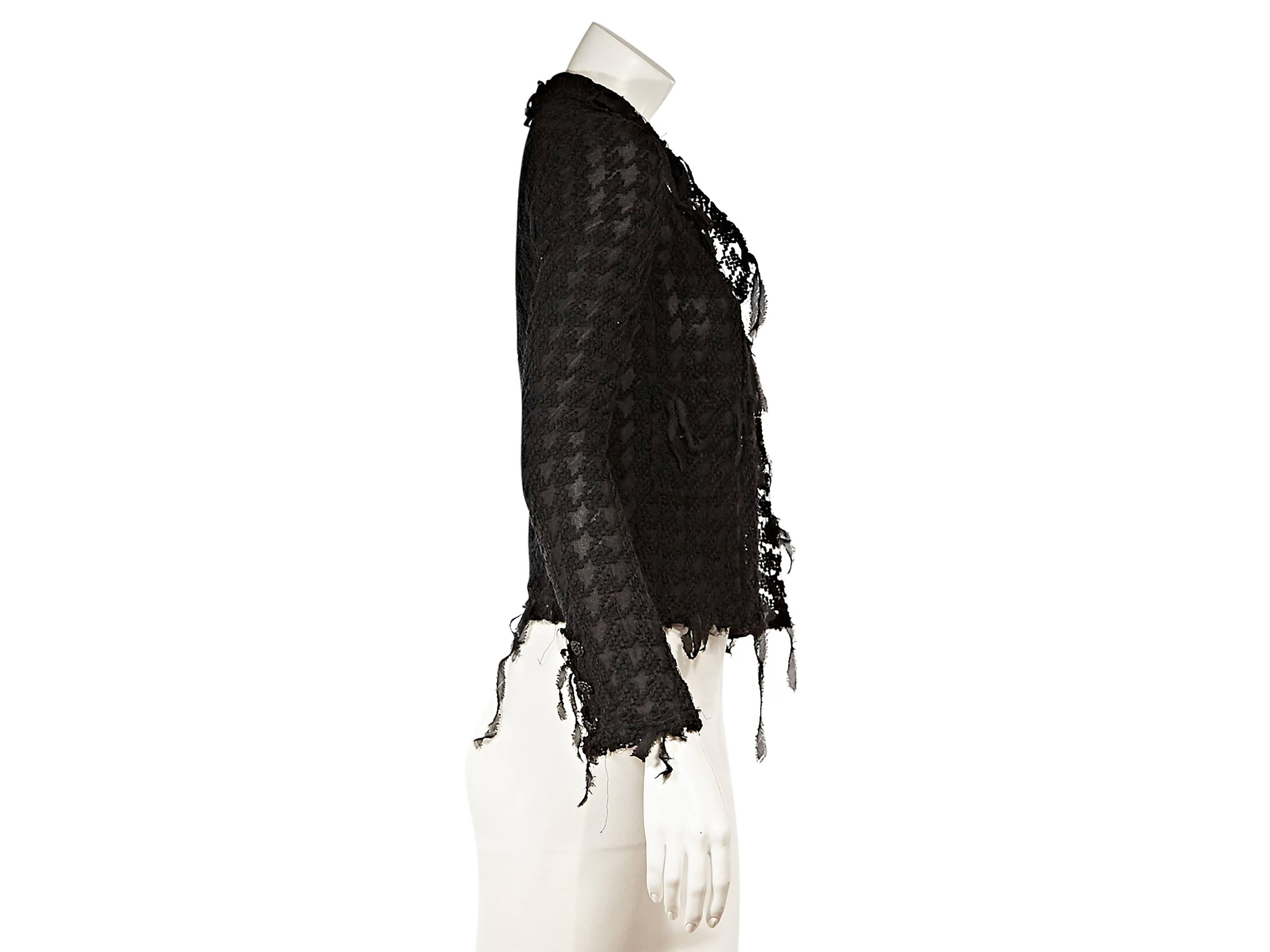 Black houndstooth knit cardigan by Chanel.  V-neck.  Long sleeves.  Concealed zip-front closure.  Fringe trim. 