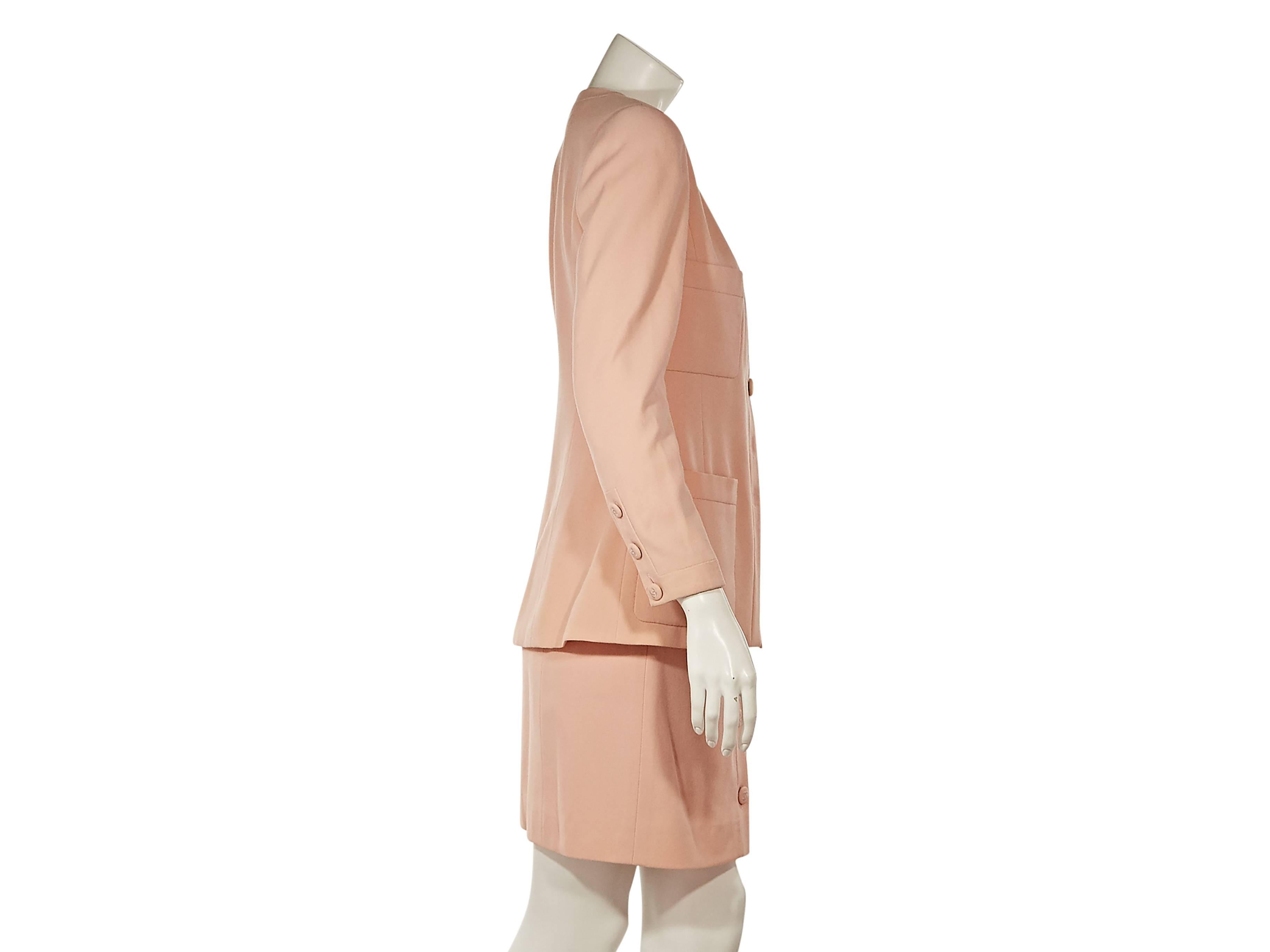 Product details:  Light pink wool skirt suit set by Chanel.  Lapel-less blazer.  Long sleeves with three-button cuffs.  Button-front closure.  Four patch pockets.  Matching skirt with banded waist.  Button-front closure.  
Condition: Excellent.  