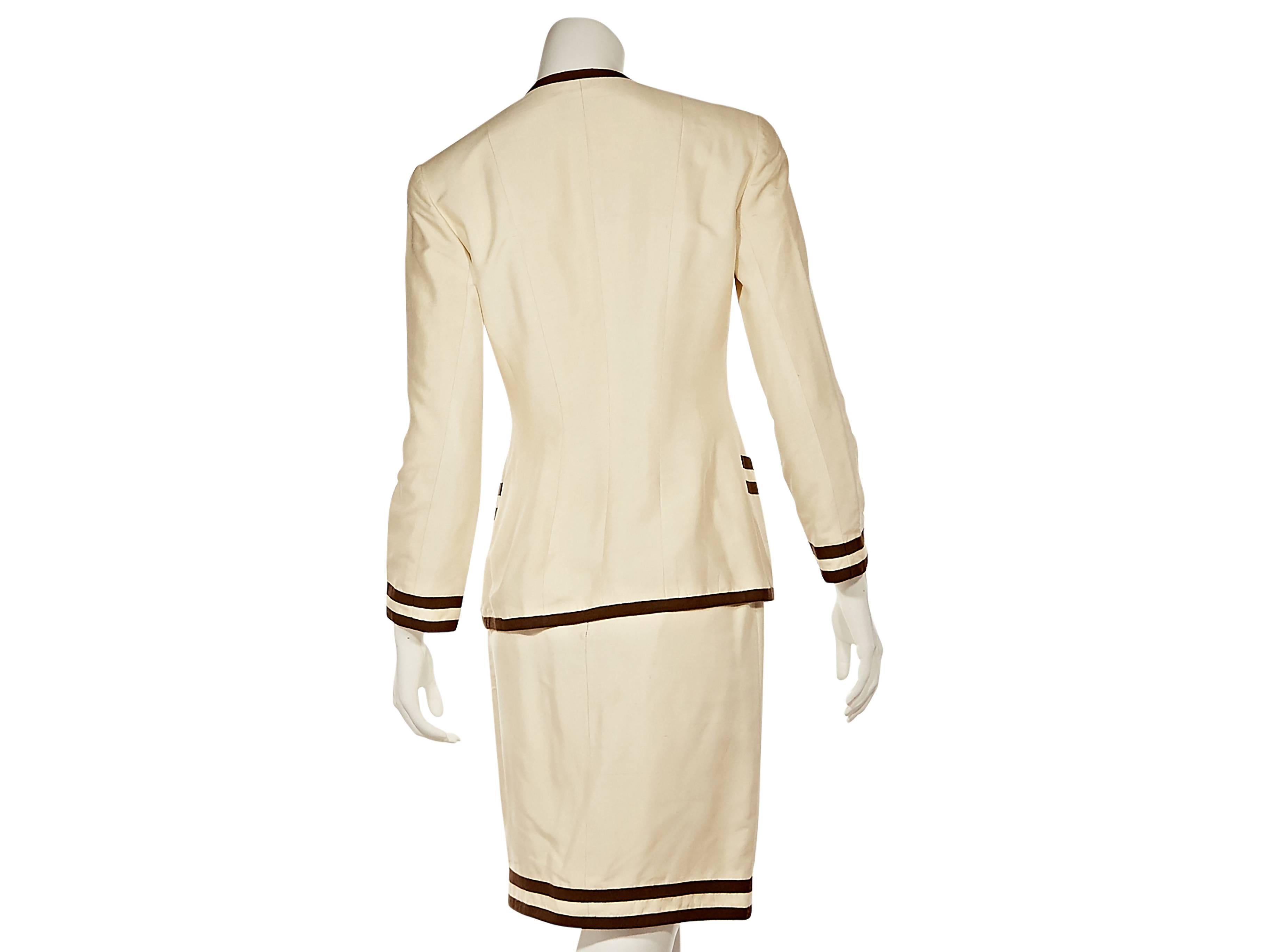 Product details:   Beige and brown skirt suit set by Chanel.  V-neck.  Button-front closure.  Four patch pockets.  Matching pencil skirt. 
Condition: Excellent.  