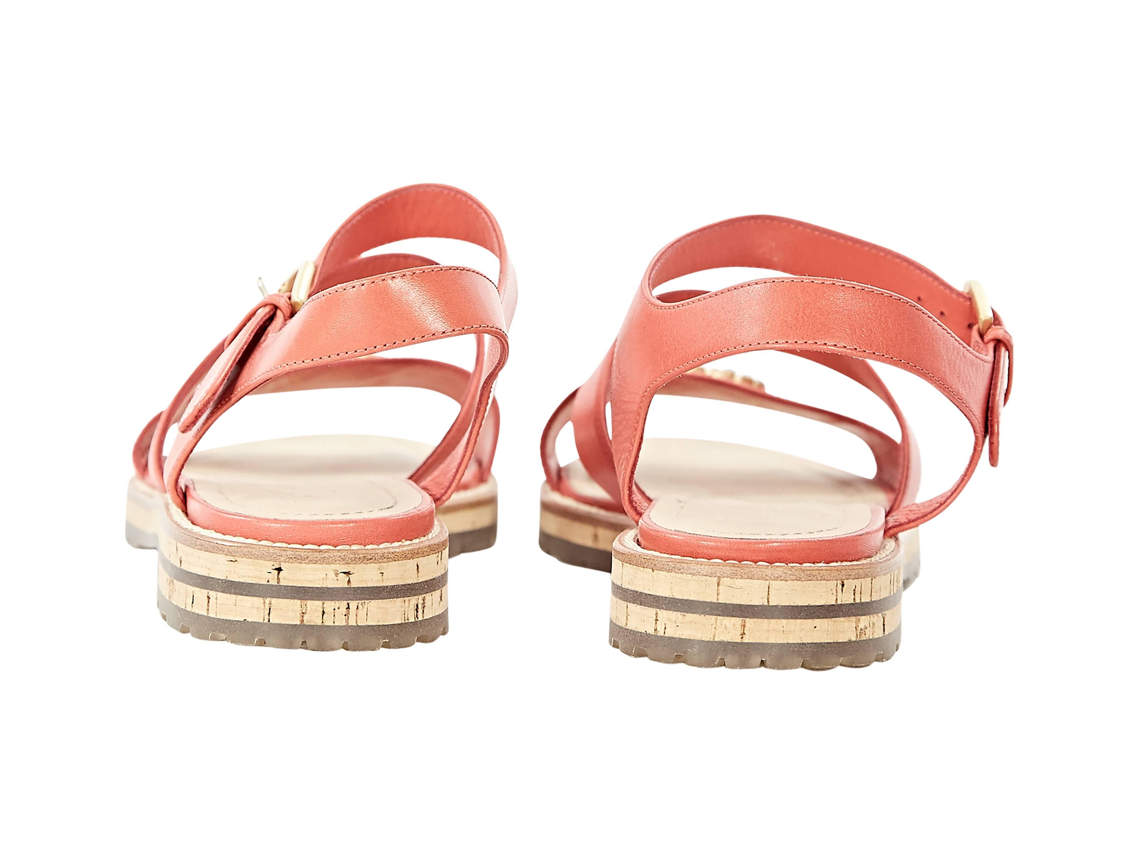 Product details:  ﻿Coral leather flat sandals by Chanel.  Adjustable ankle strap.  Open toe.   Embellished logo accents vamp strap.
Condition: Excellent.  
