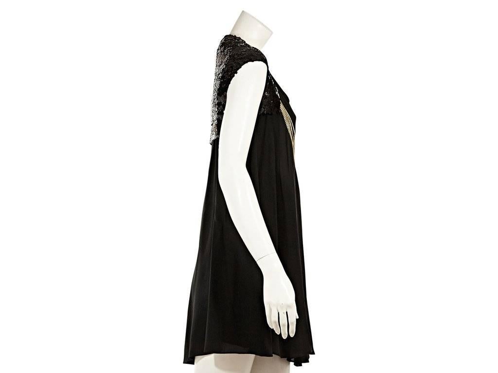 Product details:  Black silk baby doll dress by Chanel.  Sequin and chain embellishments.  Draped neckline.  Cap sleeves.  Concealed back zip closure. 
Condition: Excellent.  