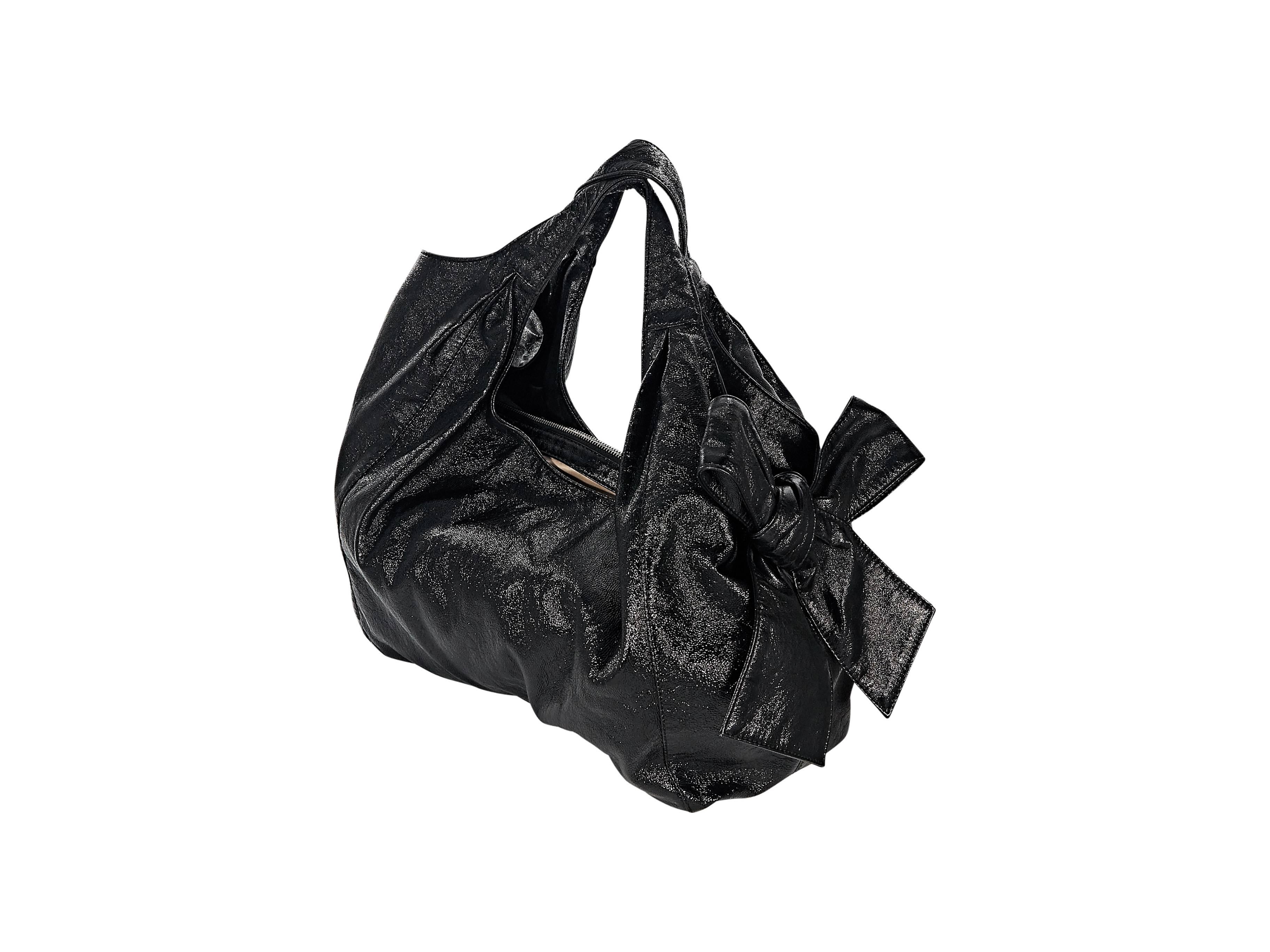 Product details: Black patent leather Nuage bow bag by Valentino. Dual carry straps. Magnetic snap closure. Lined interior with center zip divider and zip pocket. Silvertone hardware. 14"L x 11"H x 6"D. 10" strap