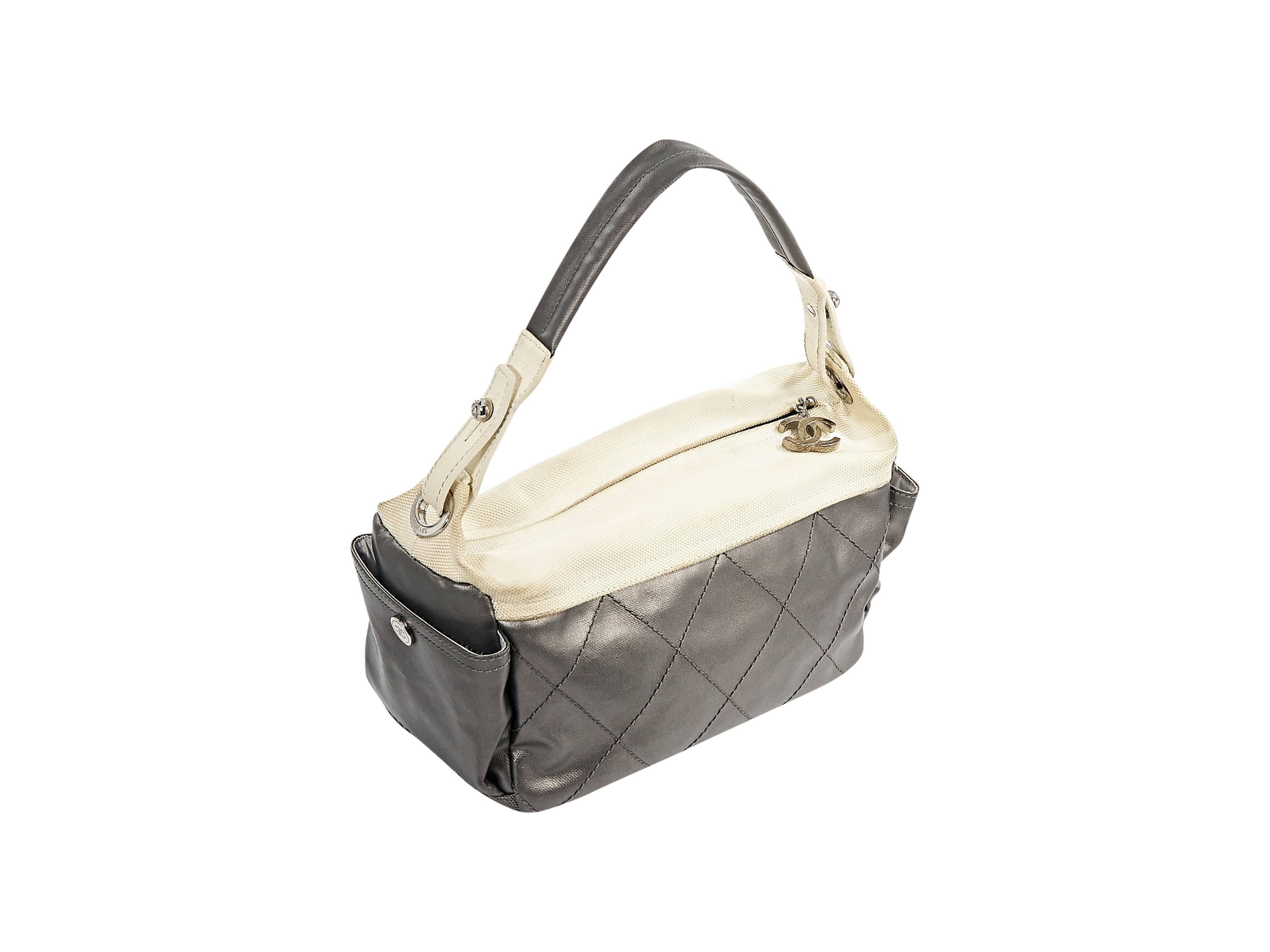 Product details: Grey quilted leather shoulder bag by Chanel. Cream canvas trim. Single shoulder strap. Top zip closure. Side pockets. Lined interior with inner zip pocket and strap. Protective metal feet. Silvertone hardware. 12