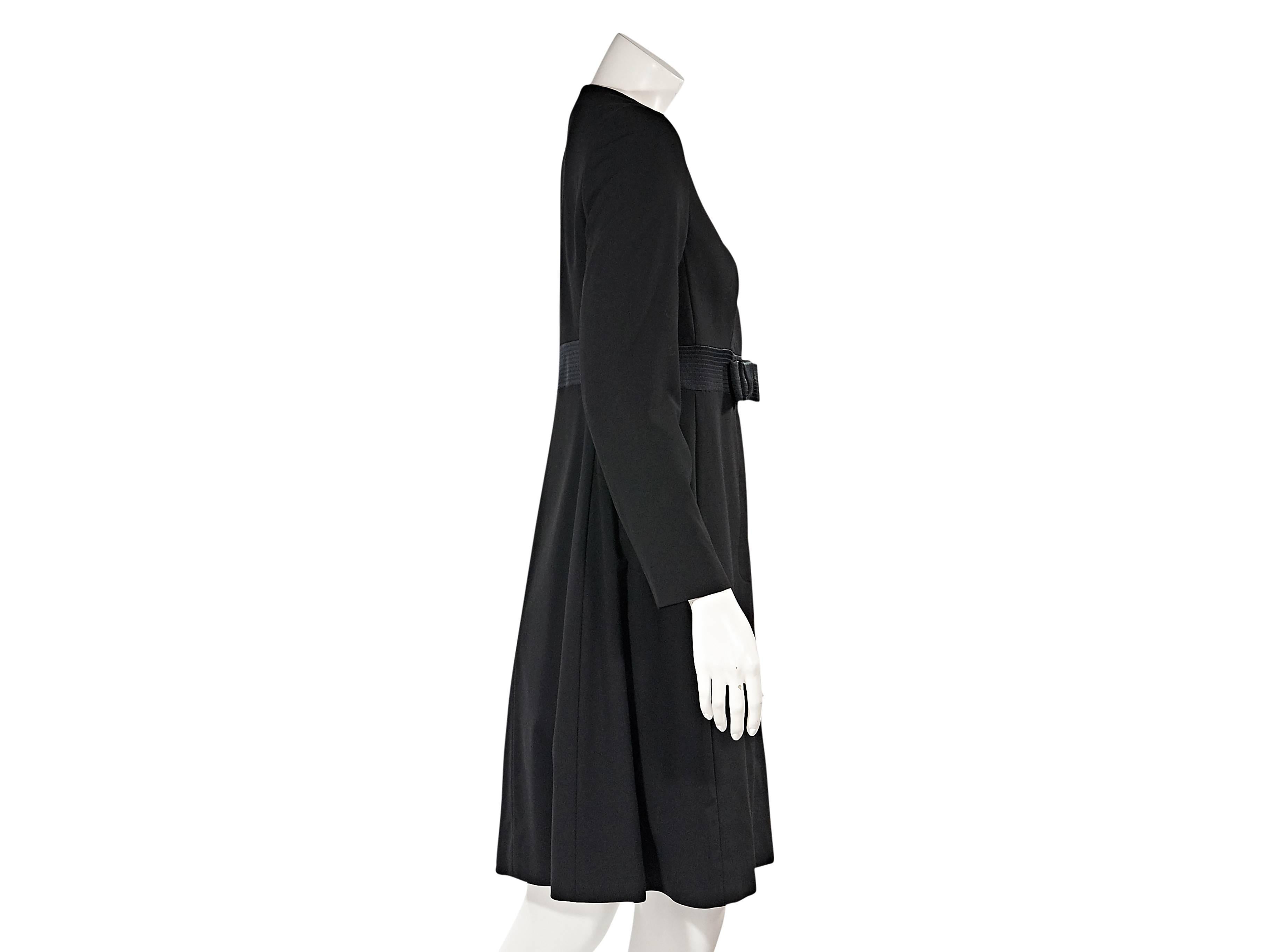 Product details:  ﻿Black wool coat by Celine.  Jewelneck.  Long sleeves.  Concealed snap front closure.  Banded waist accented with a bow. 
Condition: Excellent. 
Estimated retail: $2995