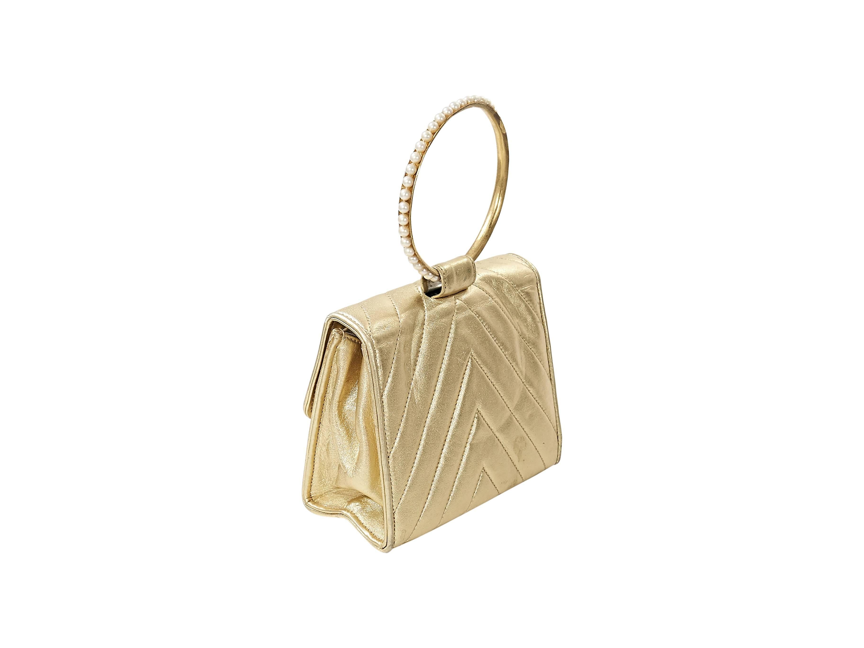 Product details:  Metallic gold quilted leather evening bag by Chanel.  Pearl embellished top ring handle.  Front flap.  Hidden magnetic snap closure.  Lined interior with inner zip pocket.  Authenticity included. 
Condition: Very good. 