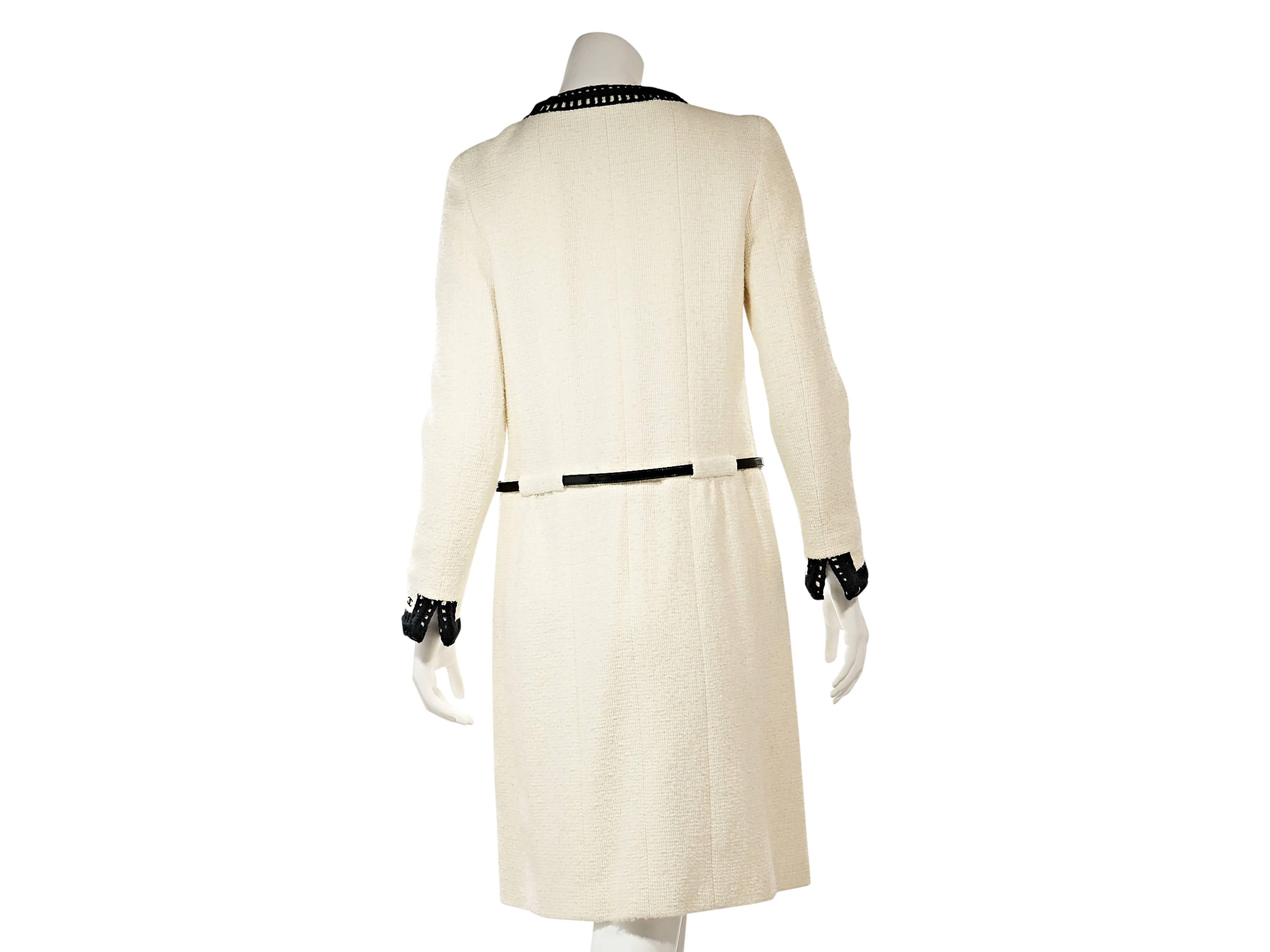 Product details:  Cream cashmere coat by Chanel.  Features black knit trim.  Jeweleneck.  Long sleeves.  Slit cuffs.  Concealed front closure.  Belted waist.  Four front patch pockets.  Label size FR 40. ﻿
Condition: Excellent. 