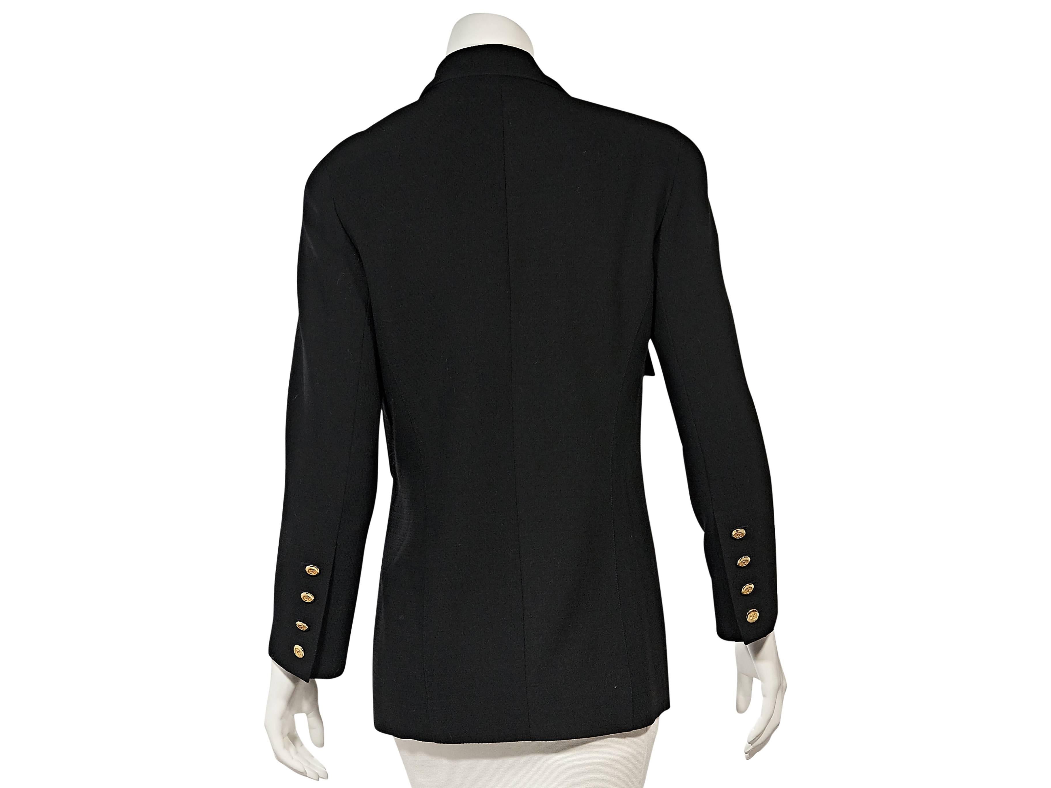 Product details: Vintage black jacket by Chanel. Peaked lapel. Long sleeves. Four-button detail at cuffs. Double-breasted button front. Chest button flap pockets. 
Condition: Very good. 