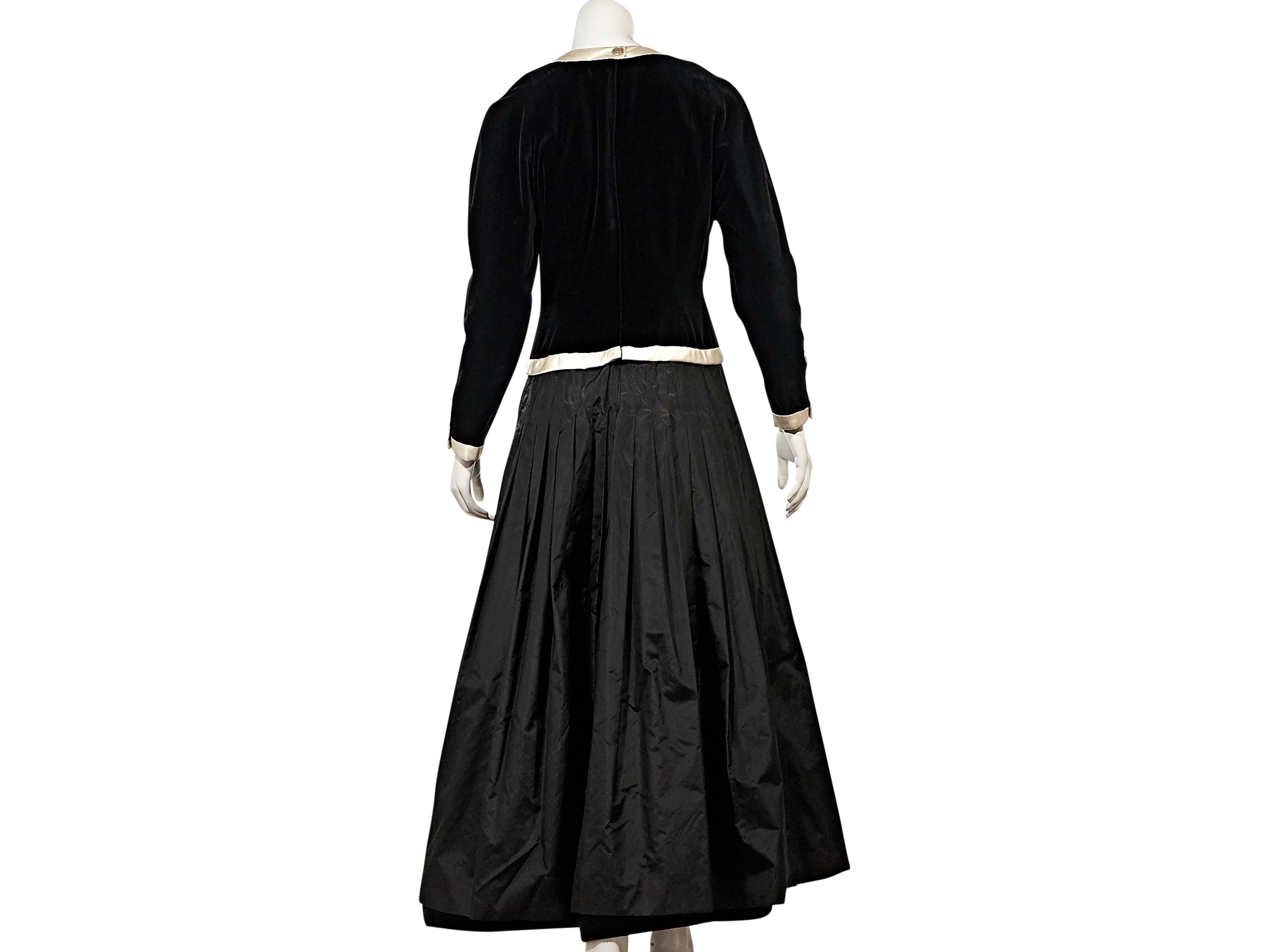 Product details:  Vintage black twofer dress by Chanel.  Designed as the look of separates.  Wide scoopneck.  Long sleeves.  Button-front closure.  Velvet bodice with trim.  Maxi pleated A-line skirting.     
Condition: Very good. 