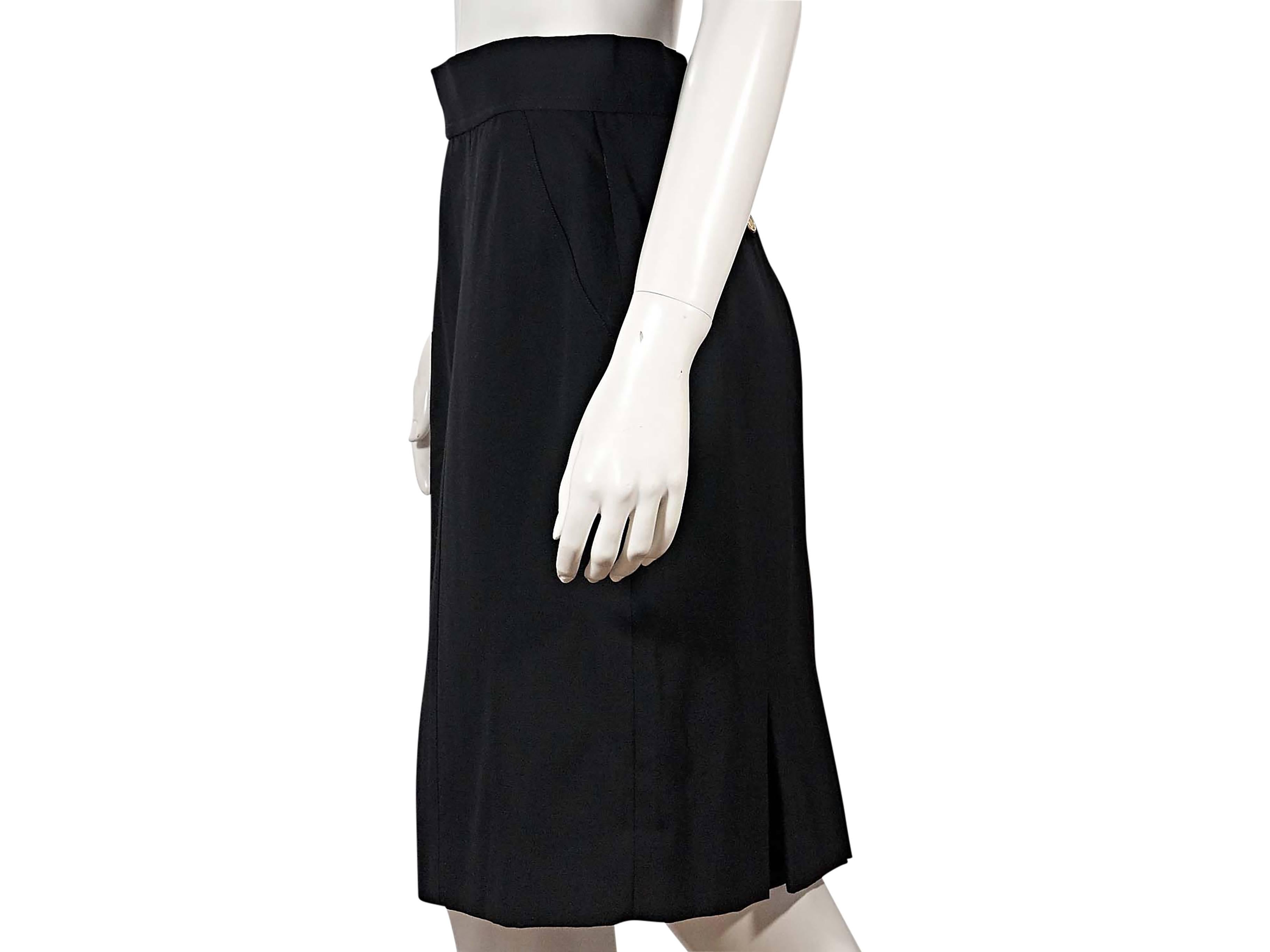 Product details:  Vintage black skirt by Chanel.  Banded waist.  Double button and concealed back zip closure.  Back besom button pockets.  Back inverted pleat hem vent.  
Condition: Very good. 