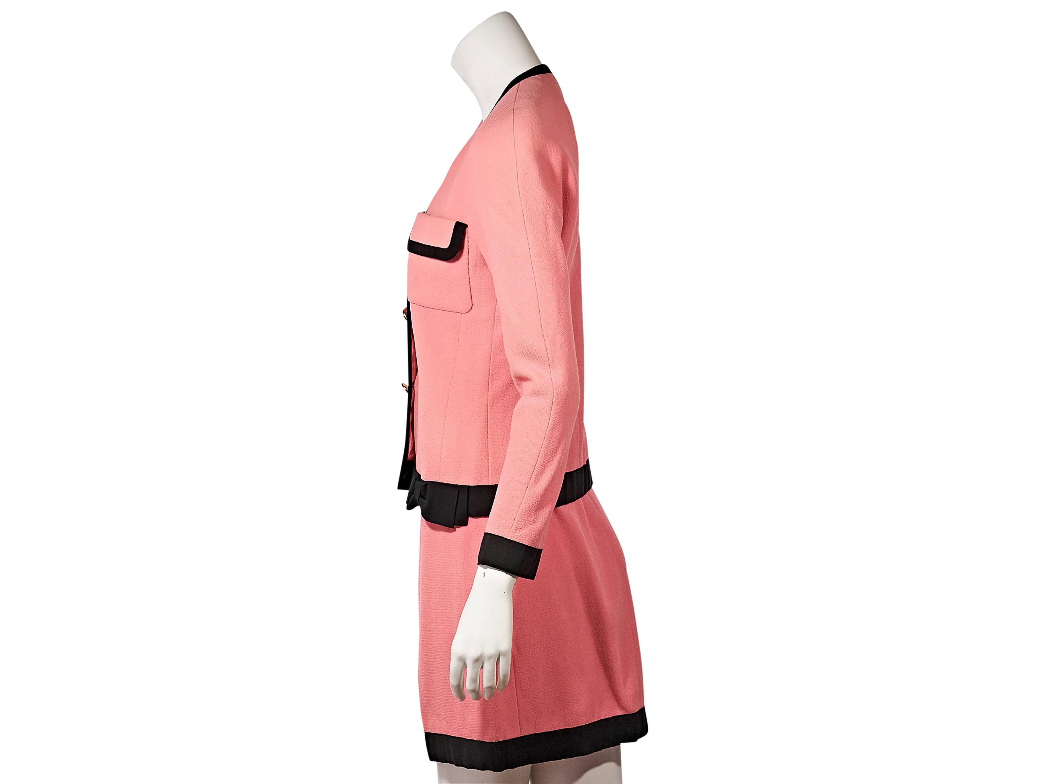 Product details: Vintage bright pink skirt suit set by Chanel. Trimmed with black grosgrain. Bracelet-length sleeves. Double-breasted button-front closure. Chest flap pockets. Matching skirt. Banded waist. 
Condition: Very good.