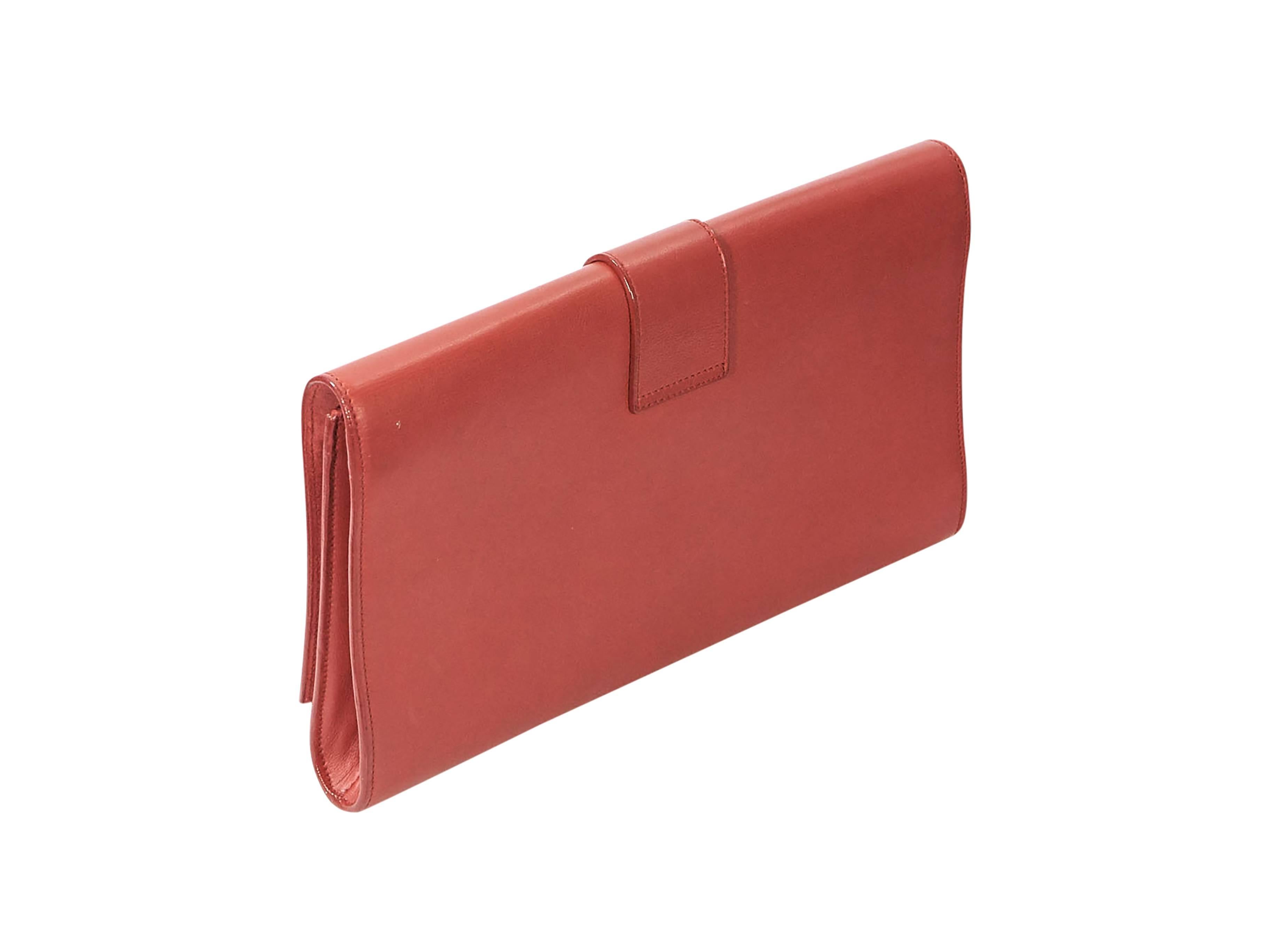 Product details: Red Chyc leather clutch by Yves Saint Laurent. Front flap with logo hardware. Magnetic snap closure. Suede lined interior with inner slide pocket. Goldtone hardware. 11.25