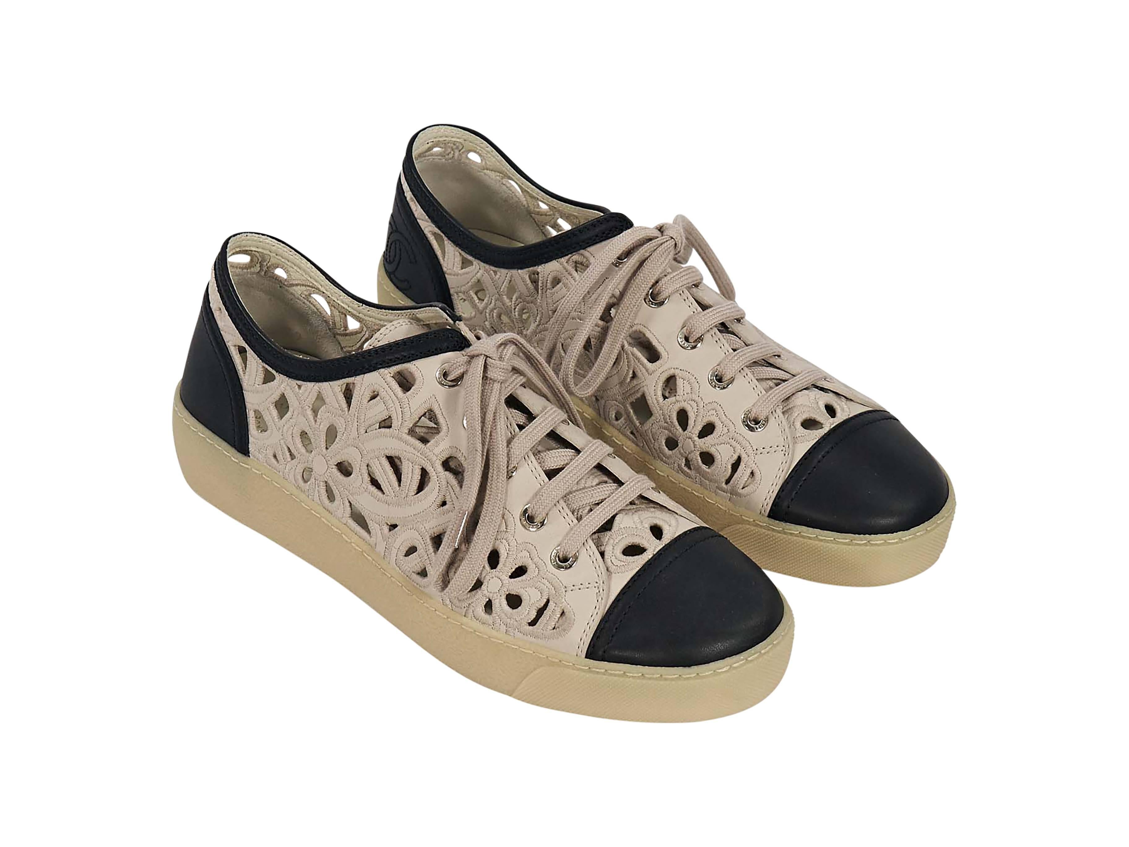 Product details: Tan and black laser-cut sneakers by Chanel. Features a floral design with embroidered trim. Lace-up closure. Round cap toe. 
Condition: Excellent. 