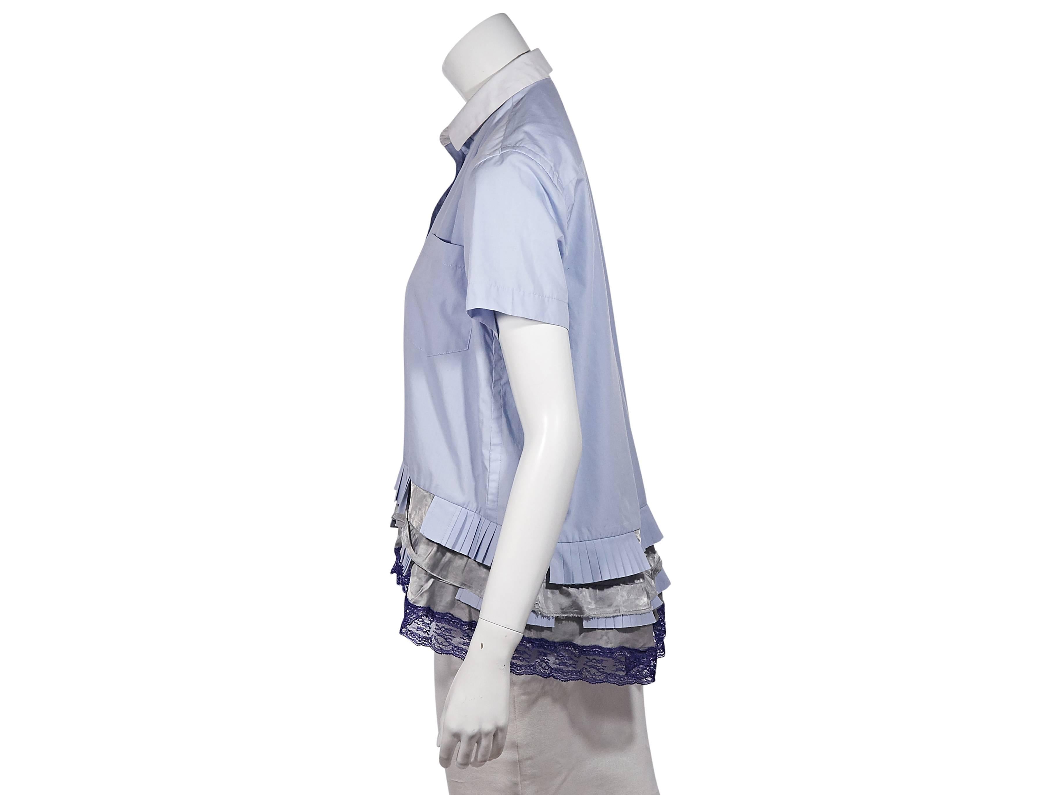 Product details: Blue ruffled and lace multicolor hem top by Sacai. Contrast point collar. Short sleeves. Button-front closure. Chest patch pocket. Back yoke with center box pleat. Tiered ruffled and lace hi-lo hem. 
Condition: Excellent. 
Est.